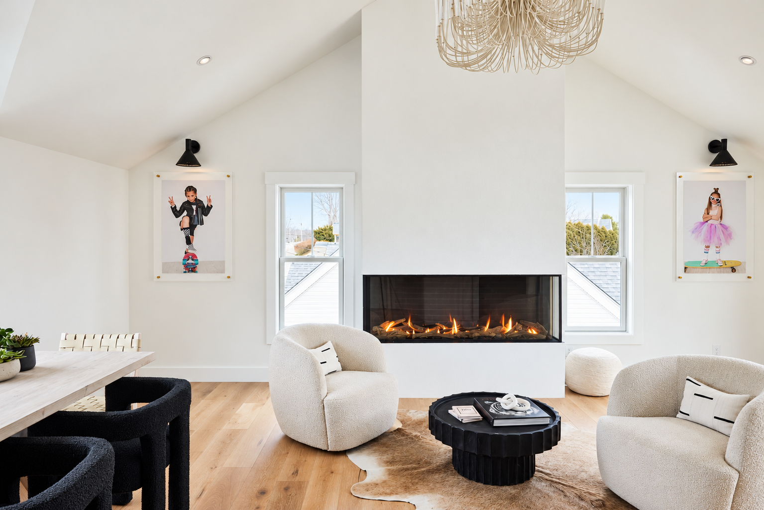 Vaulted family room with linear gas fireplace, bouclé swivel chairs, black pedestal coffee table and rattan chandelier in a Cutts Avenue home in Portsmouth, NH by Ivory & Bone Interiors
