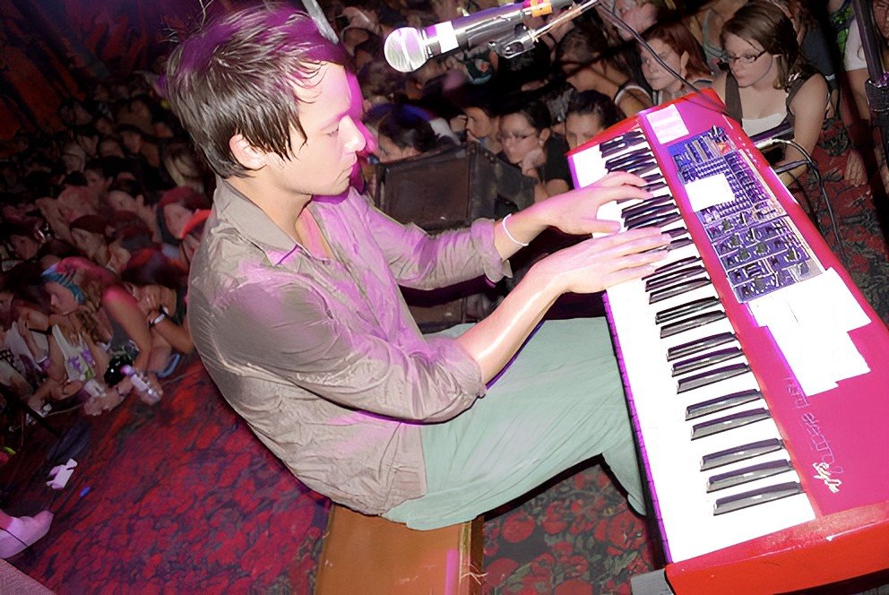Person playing a red keyboard on stage in front of an audience.