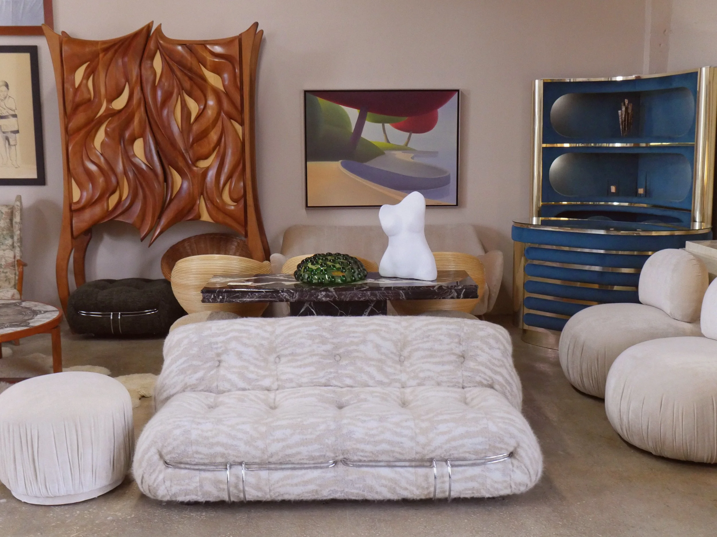 Vintage Soriana loveseat upholstered in designer Pierre Frey Wool fabric takes center stage in Casa de Barcelona's Miami showroom. Anchored by a beautiful 1970s Willy Rizzo bar, sculptural maple and cherry wood bar cabinet and a surrealist painting.