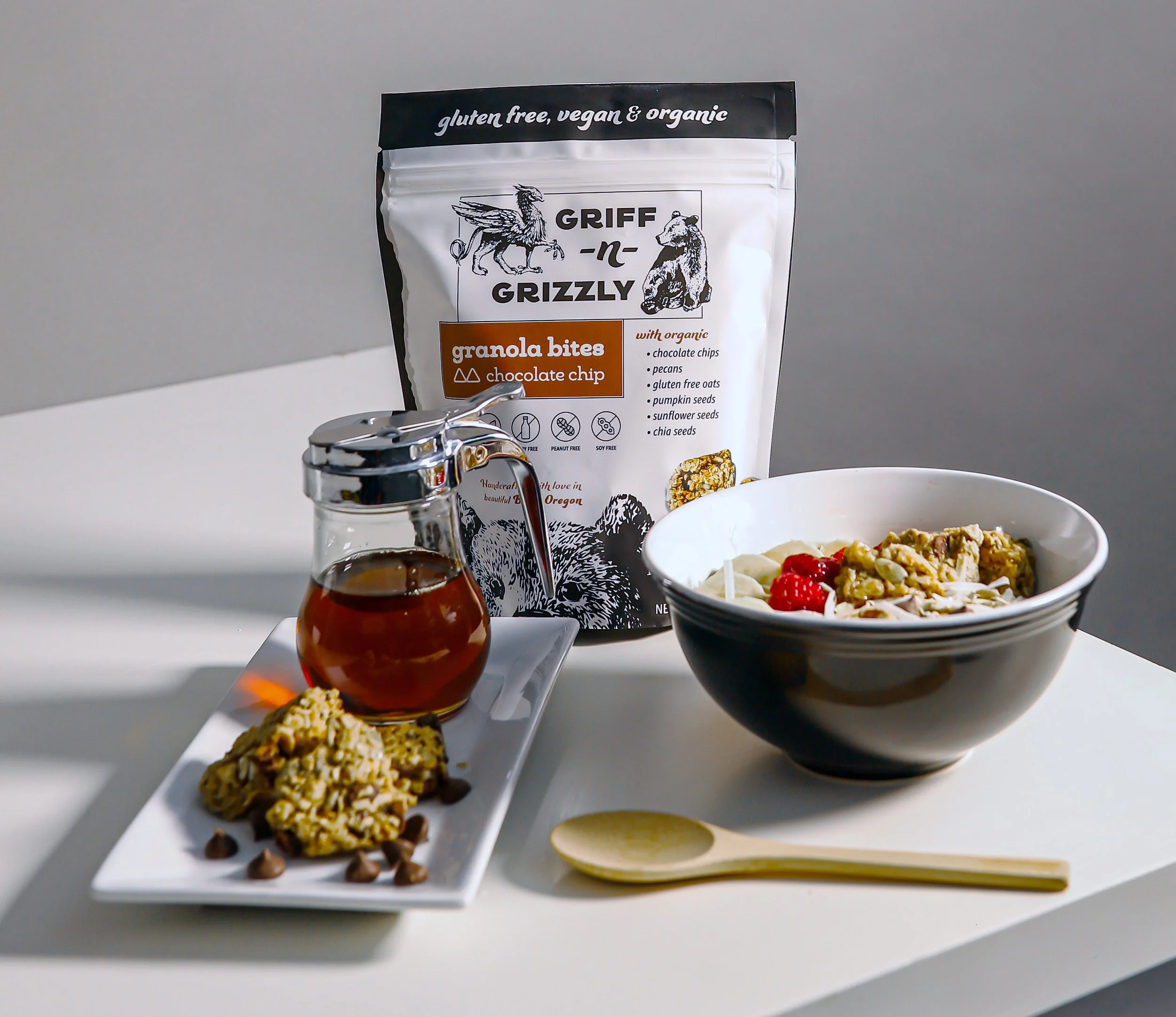 bowl of granola with raspberries next to spoon and bag