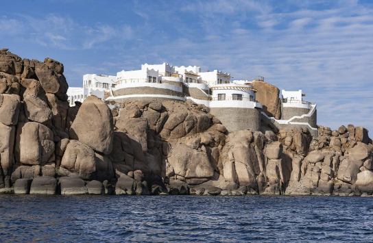White buildings on rocky cliffs overlooking the ocean.