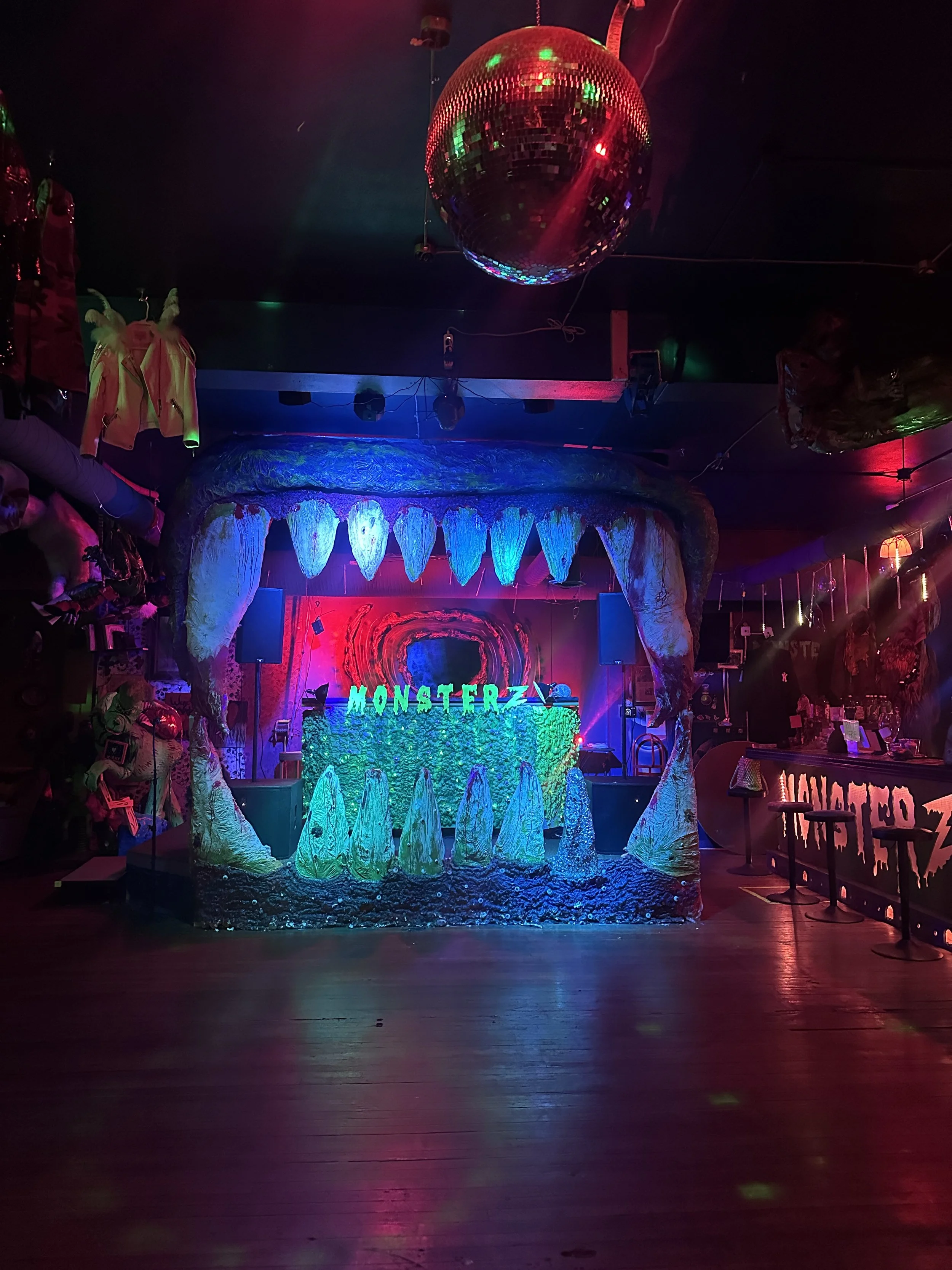 The monster disco floor and main stage at Monsterz Inc., framed by a giant mouth with teeth