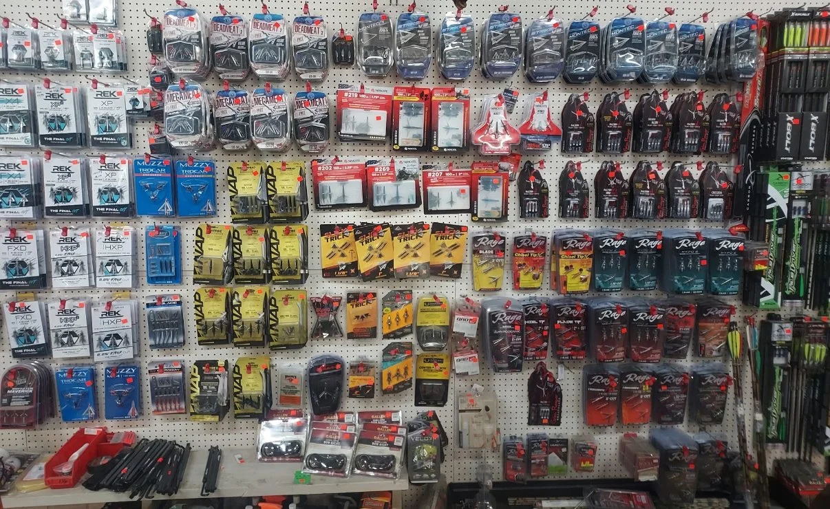 A store display wall with fishing tackle and accessories, including hooks, lures, and fishing line, arranged in packages and containers.