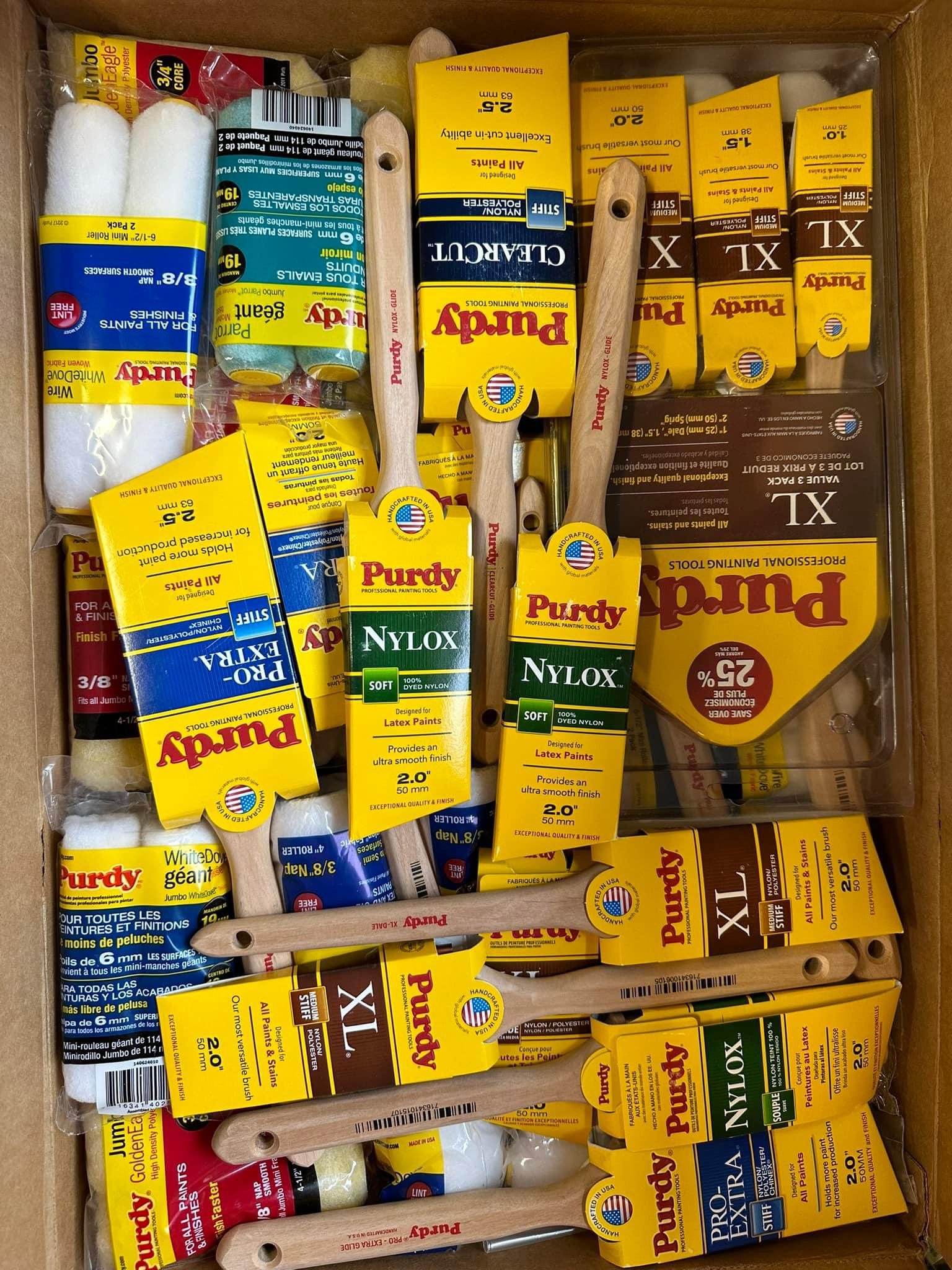 A box filled with various painting supplies including paintbrushes, paint rollers, and cans of paint.