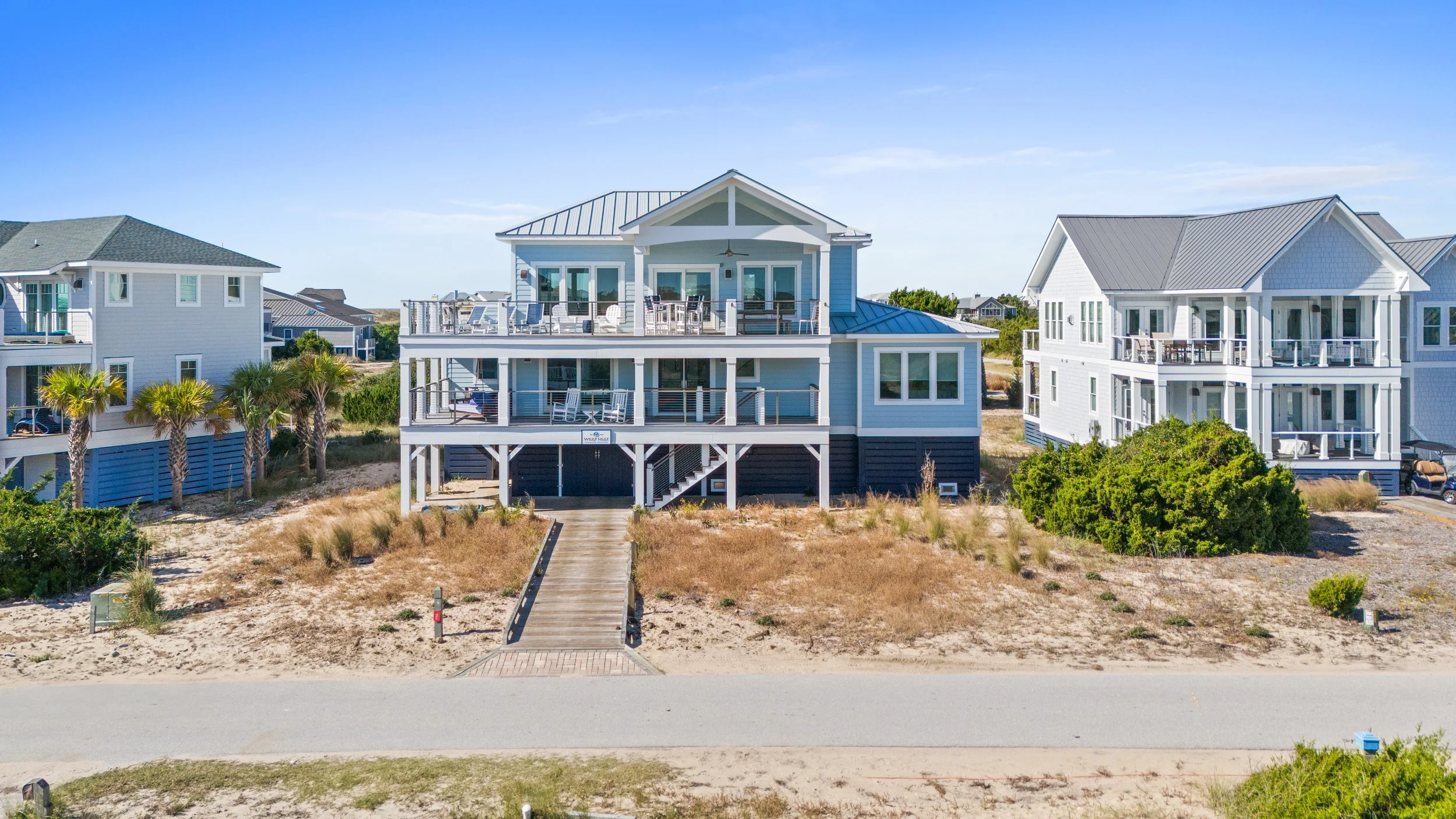 Coastal houses with large balconies overlooking the beach on sunny day.