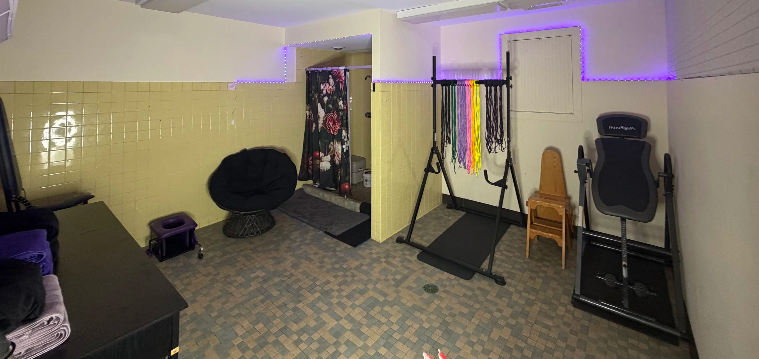 Home gym space with workout equipment, a chair, and purple LED strip lights on the walls.