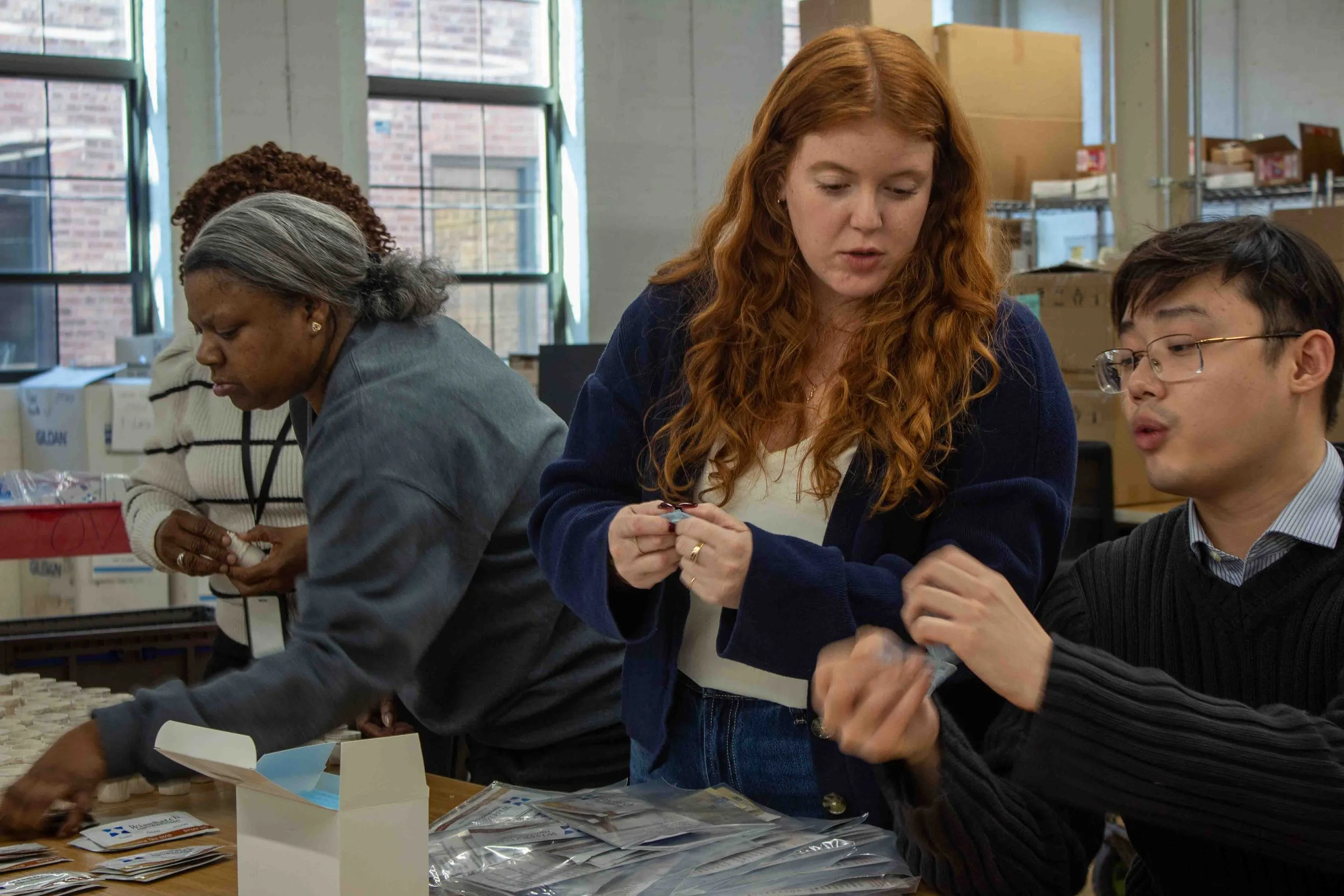 Maria Fortio packs kits with guidence from Ethan Yau 