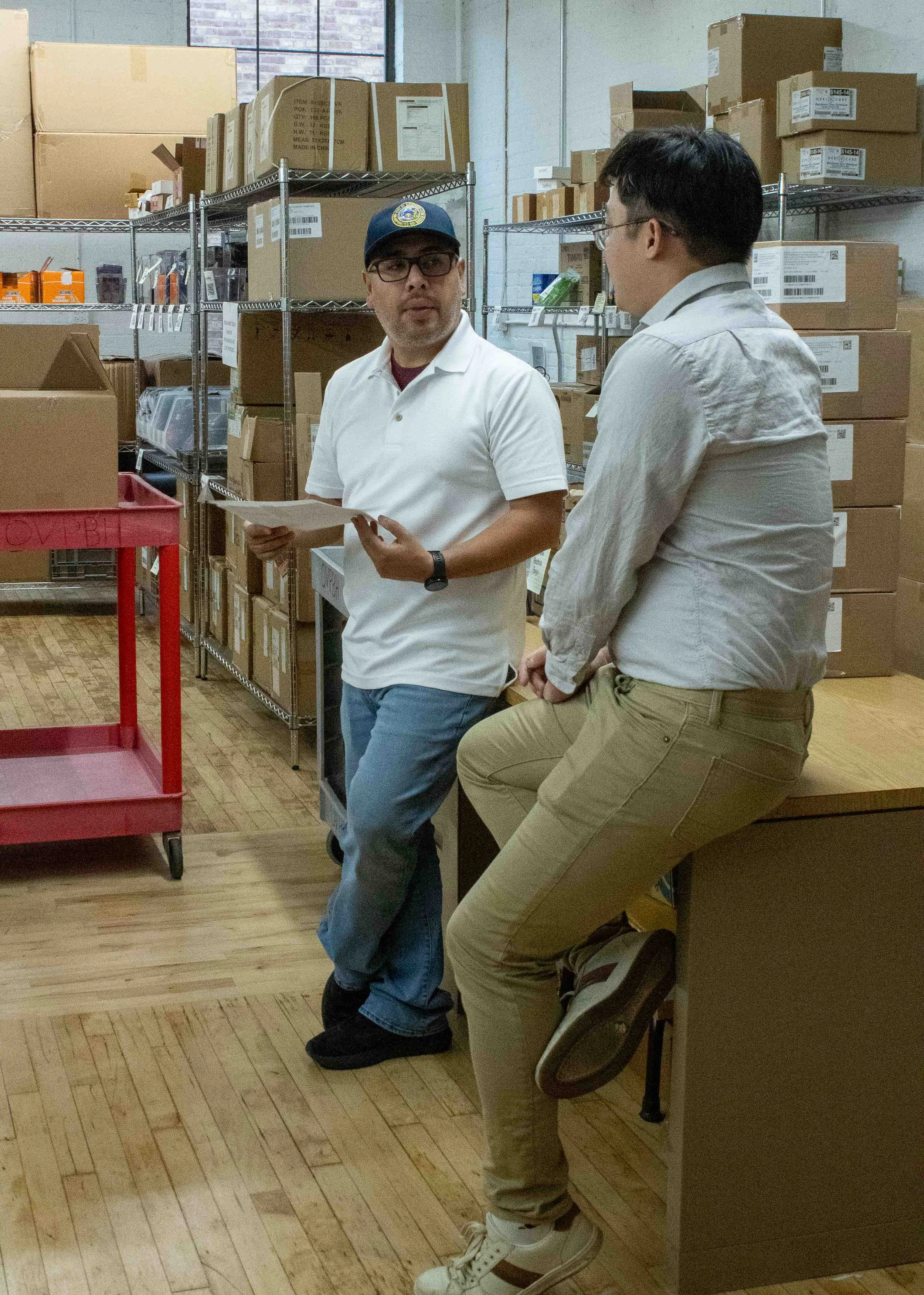 Ethan Yau and Juan Vega, both employees at the Office of Substance Abuse and Recovery chat in the supply area 