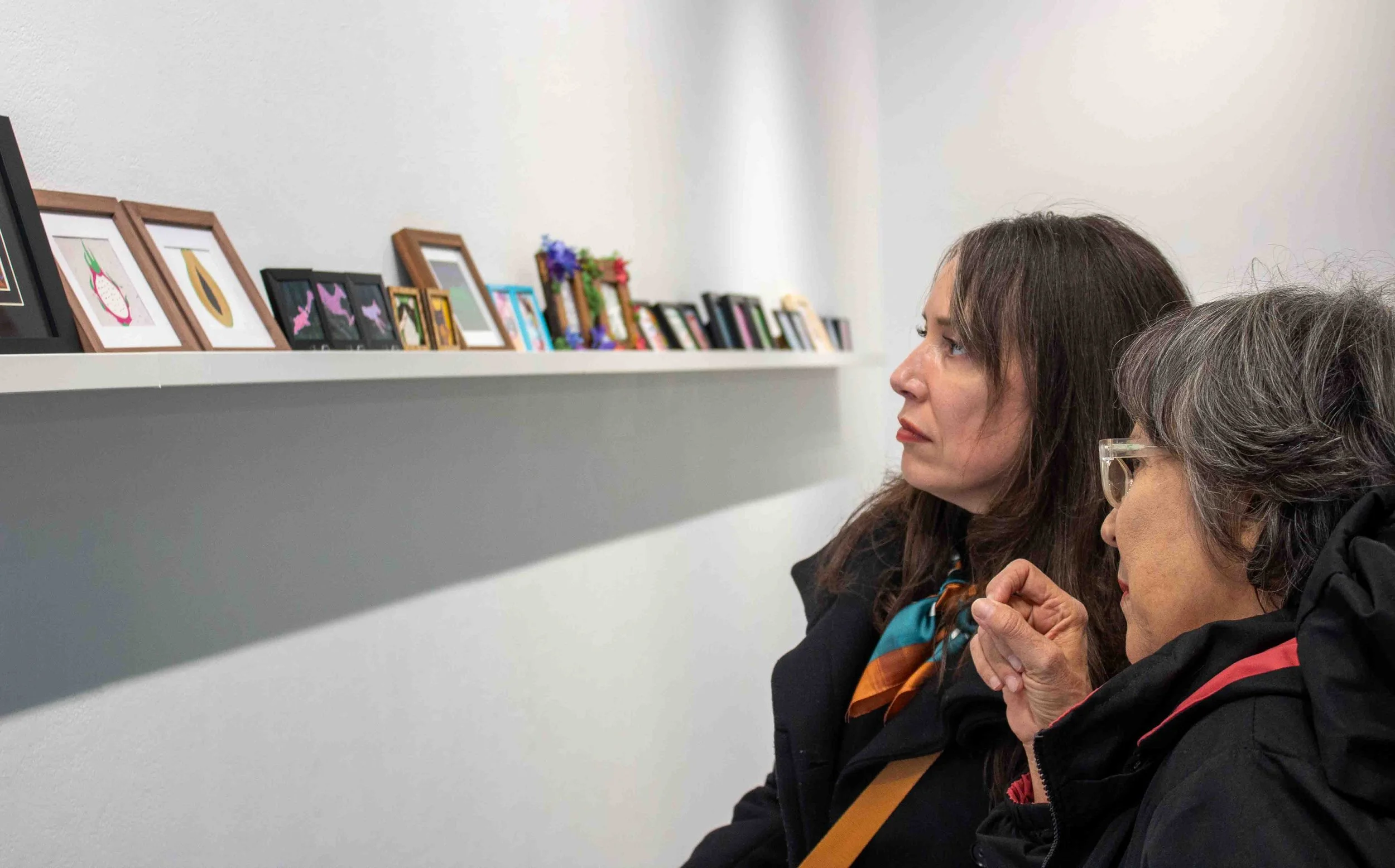Visitors to Shop Columbia Maria Lopez Garcia and her mother Magdalena Garcia view miniature art pieces lined up against the wall in the display titled “MINI MINI: A Showcase of Miniature Works” during the artist reception on Thursday, Apr. 9, 2026. 