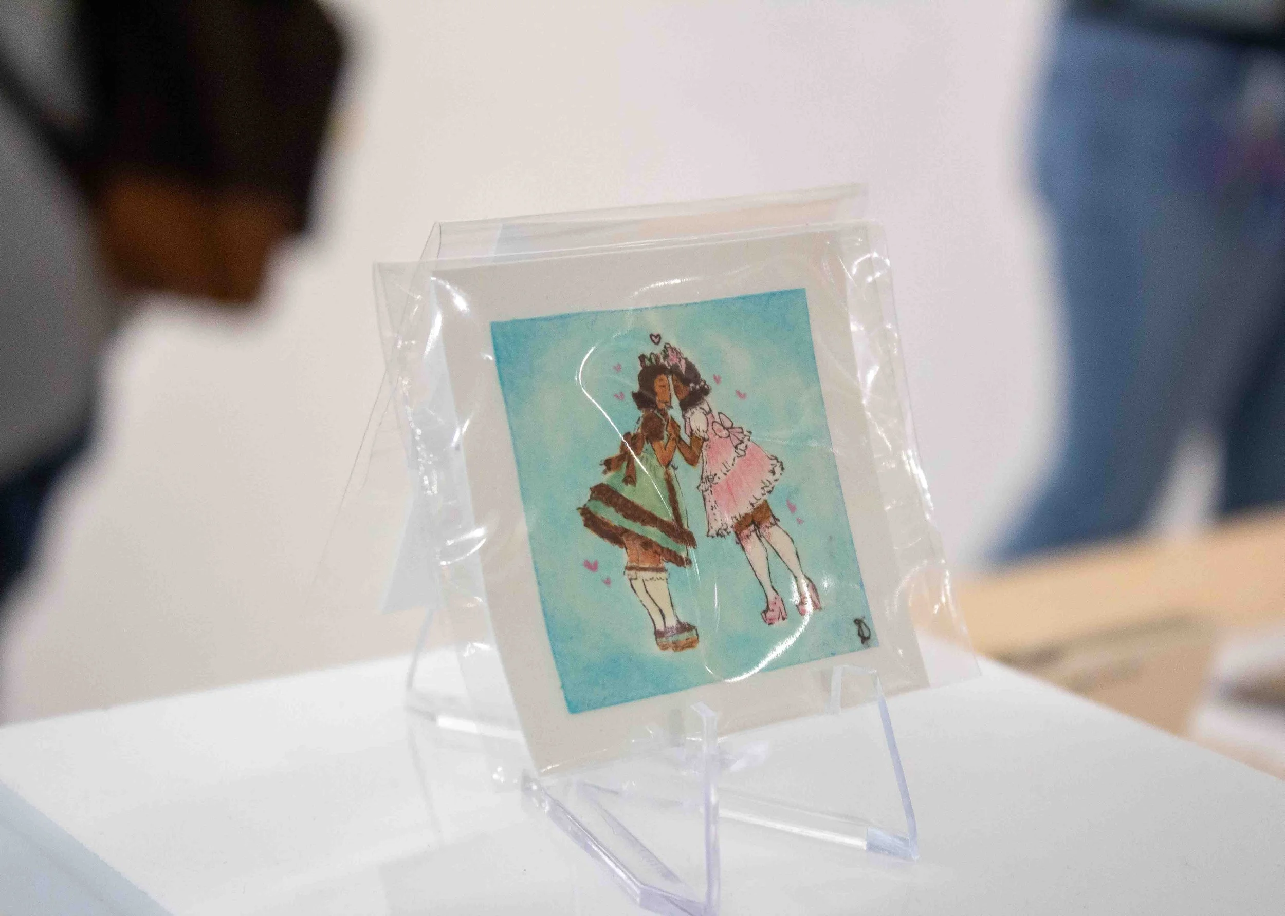“Love is So Cute” by Jocelyn Diaz is displayed on a small easel in the Shop Columbia display titled “MINI MINI: A Showcase of Miniature Works” during the artist reception on Thursday, Apr. 9, 2026. 