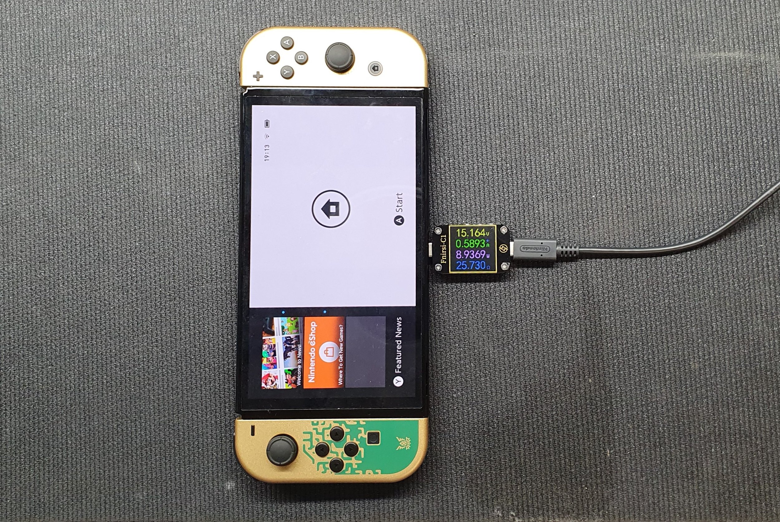 A Nintendo Switch console with a small sensor attached to one side, resting on a gray fabric surface.