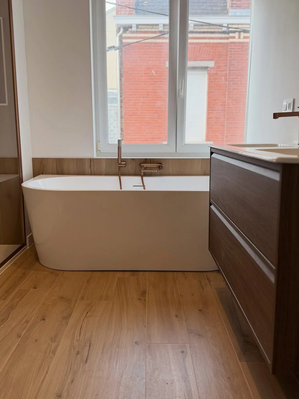 Baignoire îlot blanche sur sol parquet bois clair salle de bain La Bassée