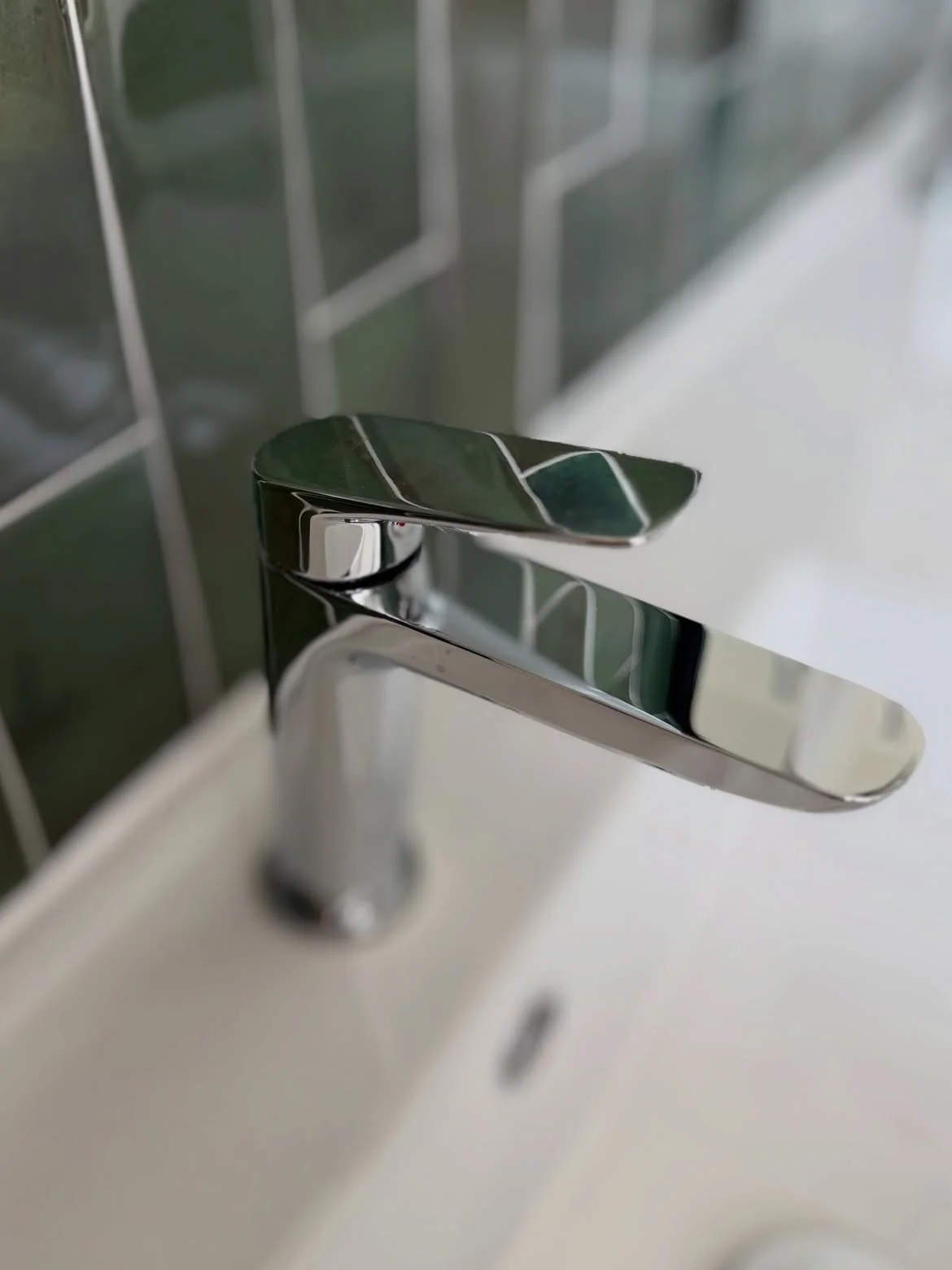 Gros plan robinetterie chromée sur carrelage vert salle de bain Hazebrouck