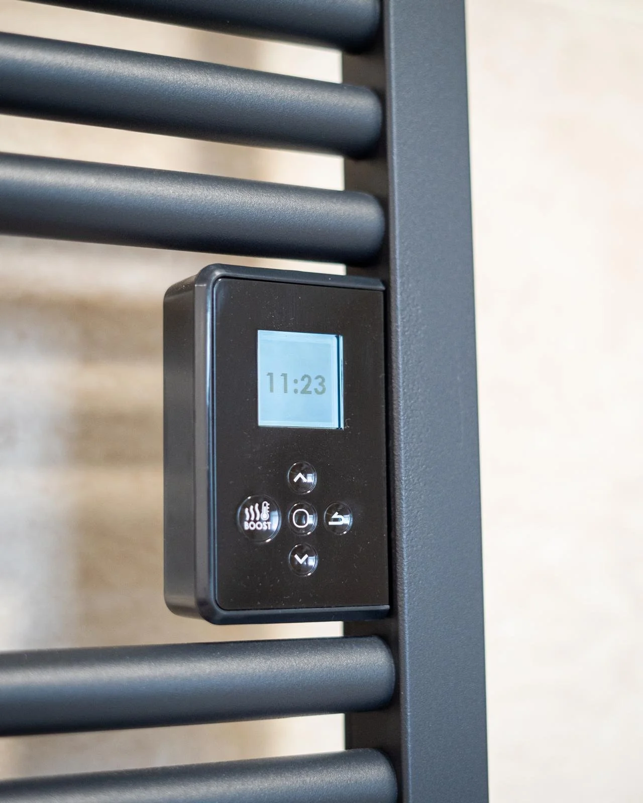 Un thermostat numérique fixé à une barre destructure en métal, affichant l'heure 11:23.