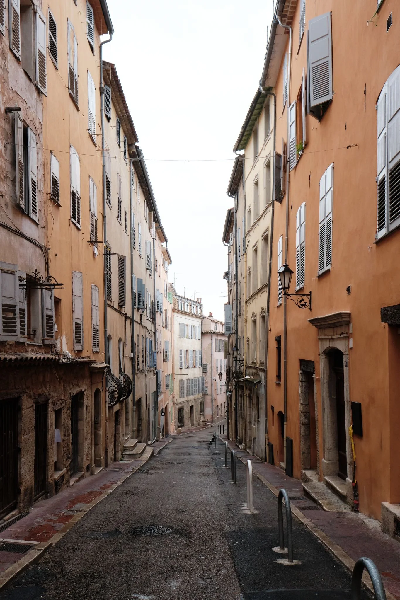 En smal gata i en äldre stad med färgglada byggnader och öppna fönsterlägenheter.