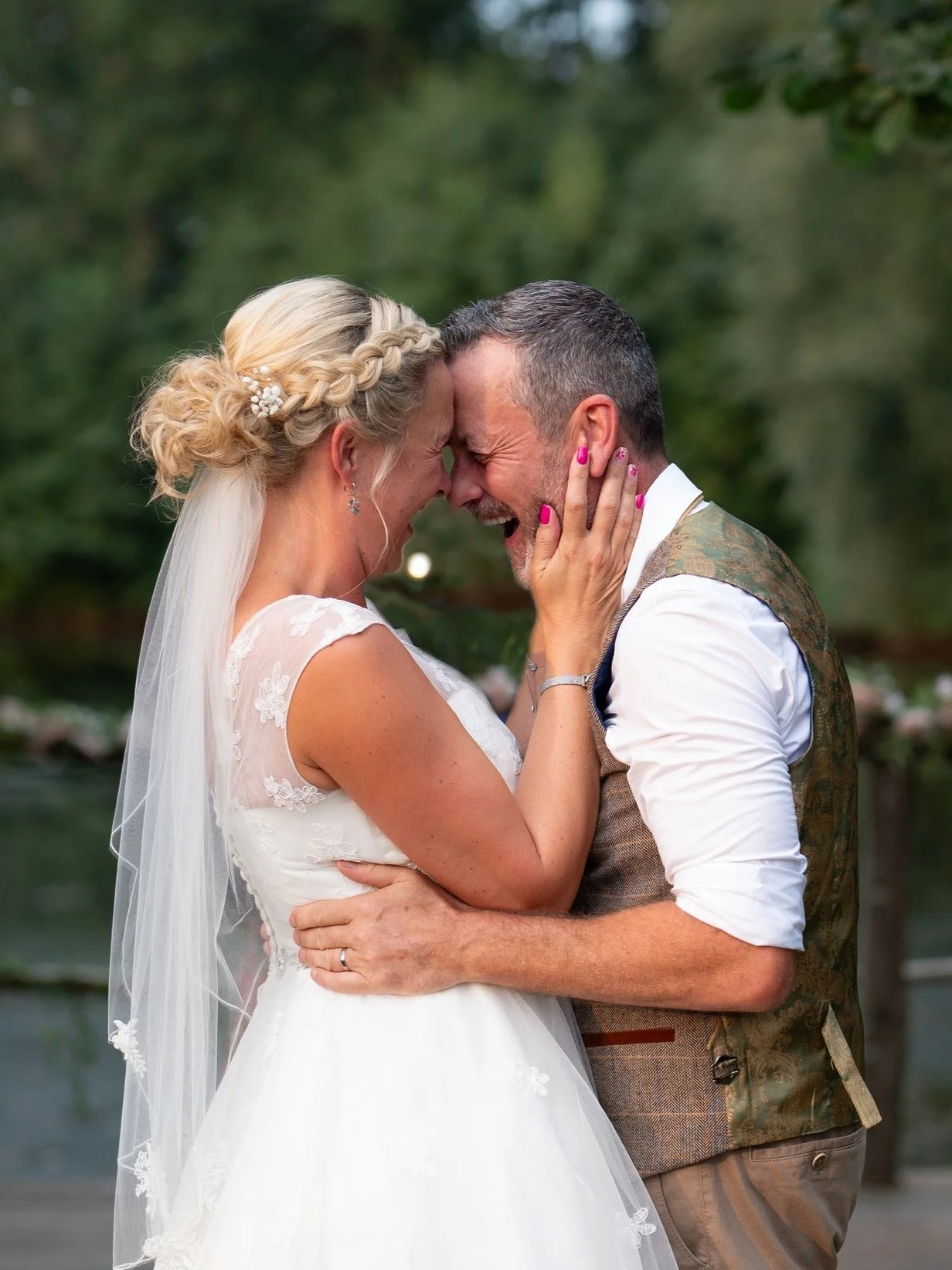 Bride and groom smiling while embracing during an outdoor wedding.