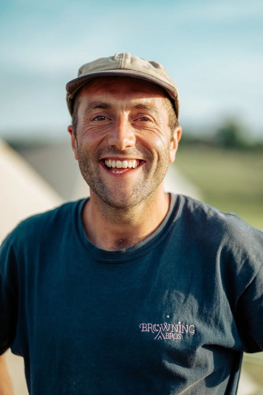 Smiling man wearing a cap and a Browning Bros T-shirt outdoors.