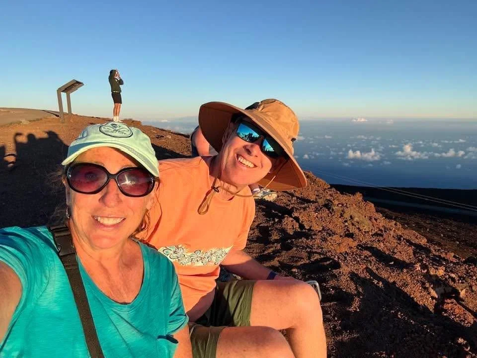 A man and a woman take a selfie at a mountaintop.