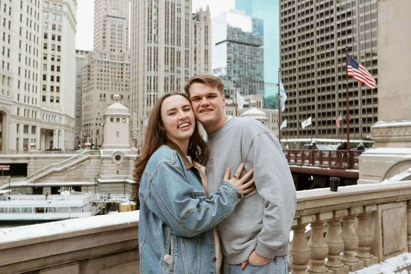 A man and woman pose for a photo in front of a cityscape.