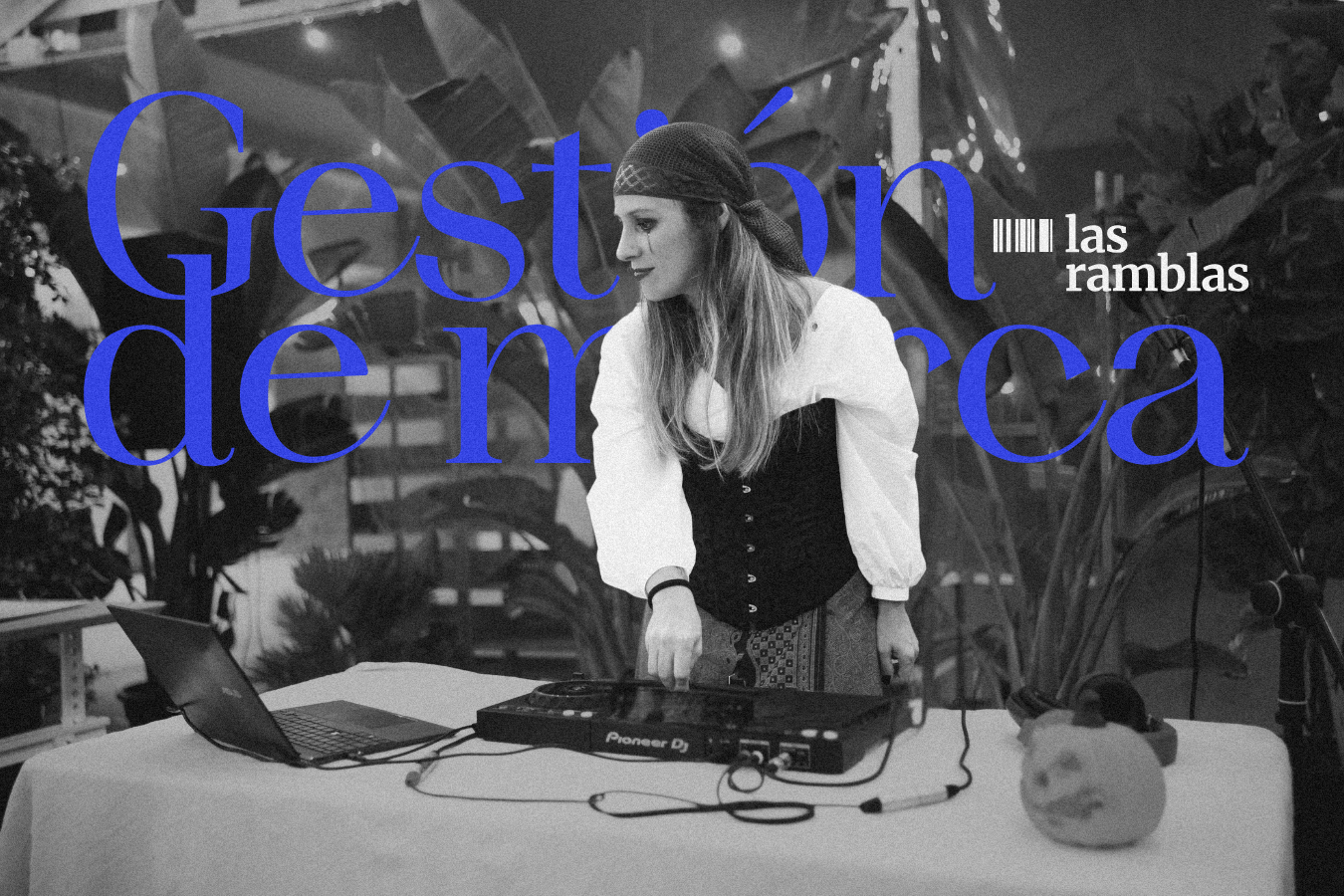 Una mujer joven con un pañuelo en la cabeza, vestida con blusa blanca y corsé negro, ajustando equipos musicales en una mesa con plantas de fondo, en un ambiente de noche para un evento llamado 'Gestaón de las Ramblas'.