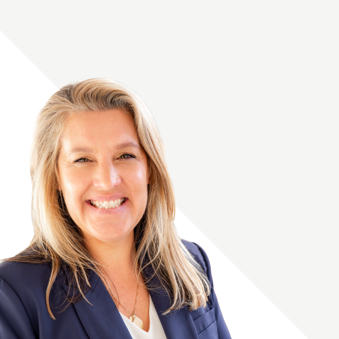Smiling woman (Abbey Danczak) with blonde hair wearing a navy blazer and white shirt, facing camera.