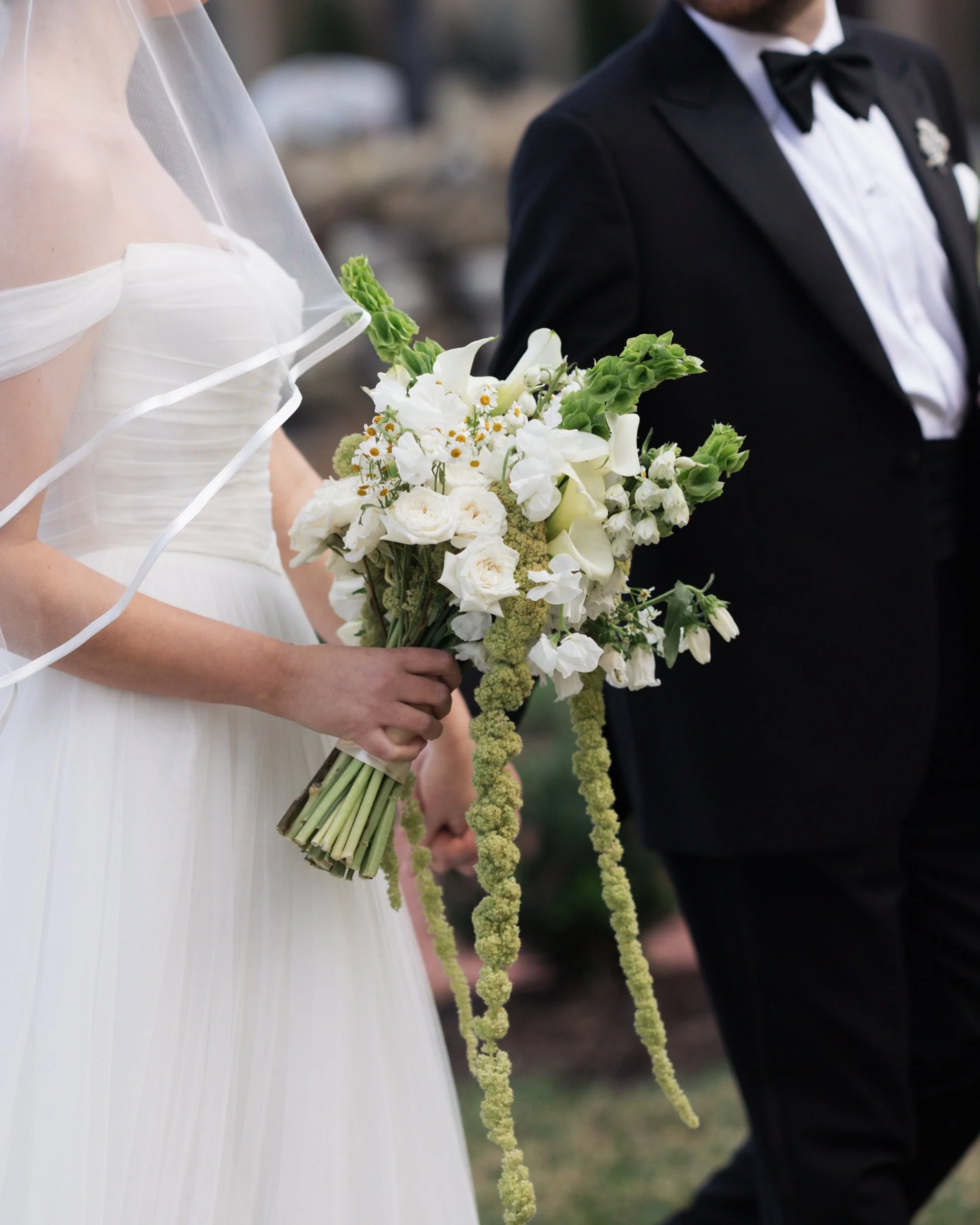 Close-up of a woman in a white wedding dress with a corset back, paired with long white gloves, sitting on a chair.