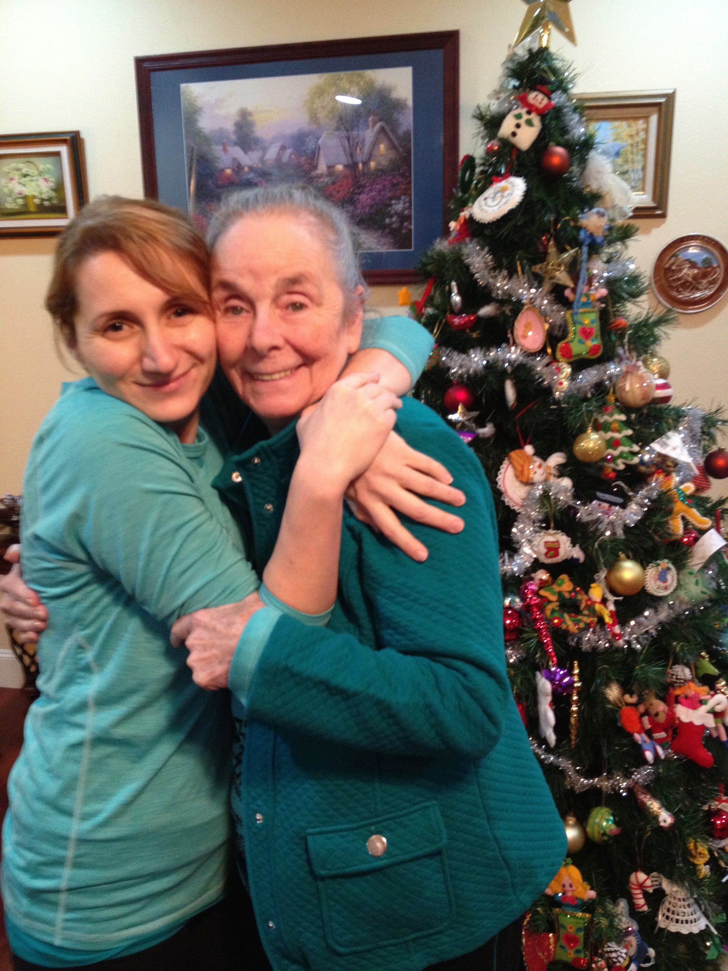 Two people hugging in front of a decorated Christmas tree.