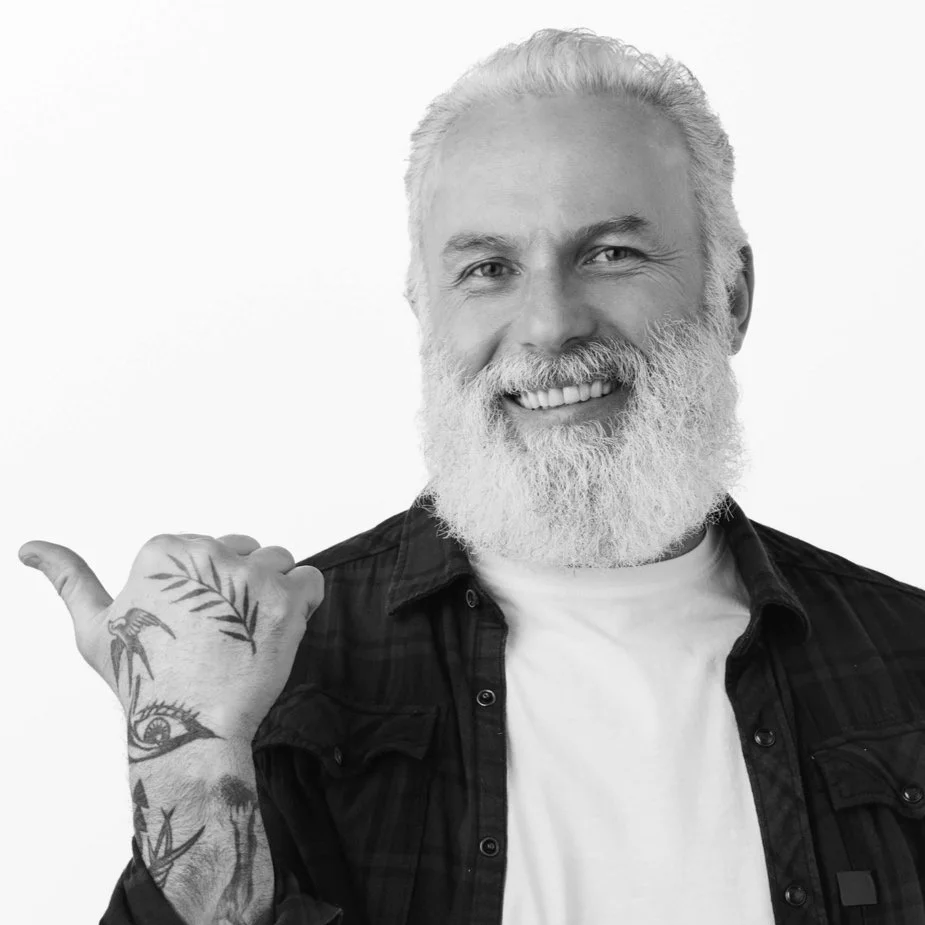 BW_stylish-old-man-senior-hipster-guy-with-beard-tattoos-pointing-finger-left-showing-promo-aside-demonstrating-advertisement-white-copy-space-studio-wall (1).jpg