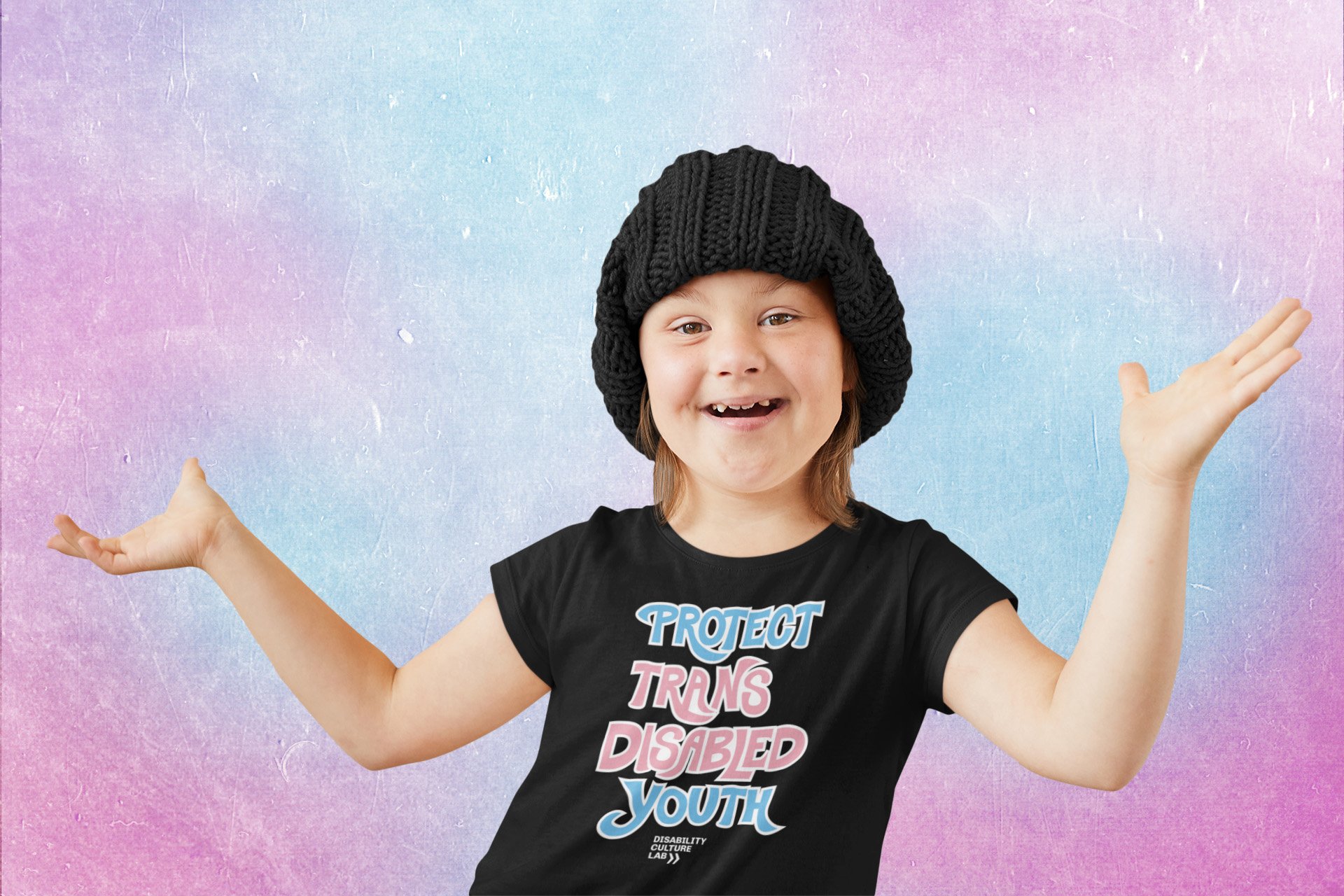 An adorable white child smiles brightly with their hands in the air. They are wearing a black knitted hat and black t-shirt that reads "Protect Trans Disabled Youth" in light blue, pink, and white hand drawn lettering.