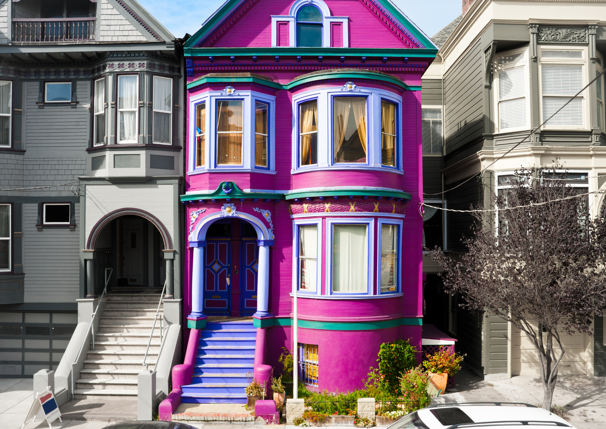 A San Francisco style pink house, in between 2 grey ones.