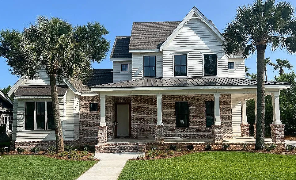 Timeless Southern style featuring a blend of brick and siding, a spacious front porch, and a modern metal roof that enhances both durability and charm.
