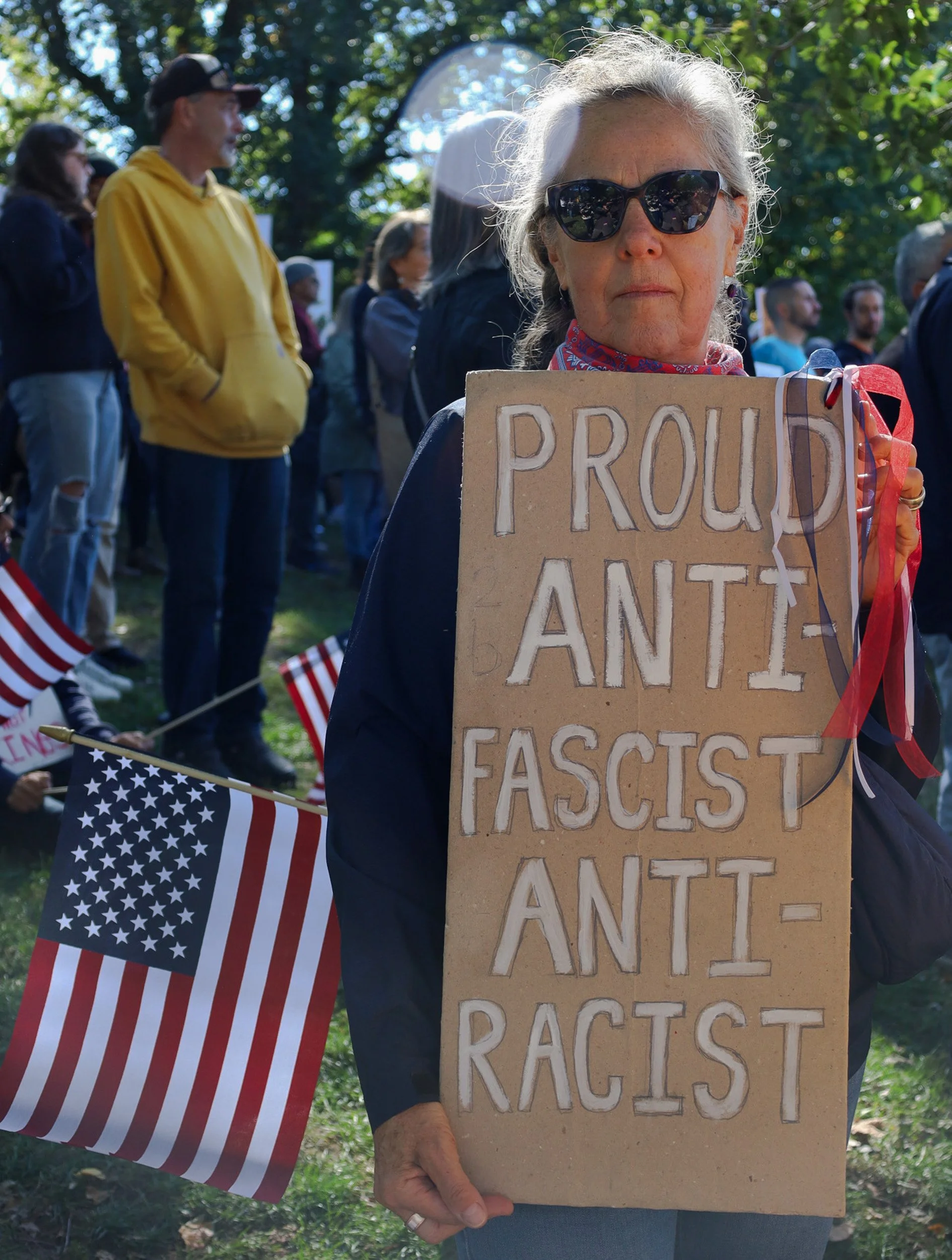 BOSTON, MA--10.18.25--Toni Elka holds a sign that says "Proud Anti-fascist/Anti-racist" while an American flag sticks out of her bag, during the No Kings Protest at the Boston Common. 