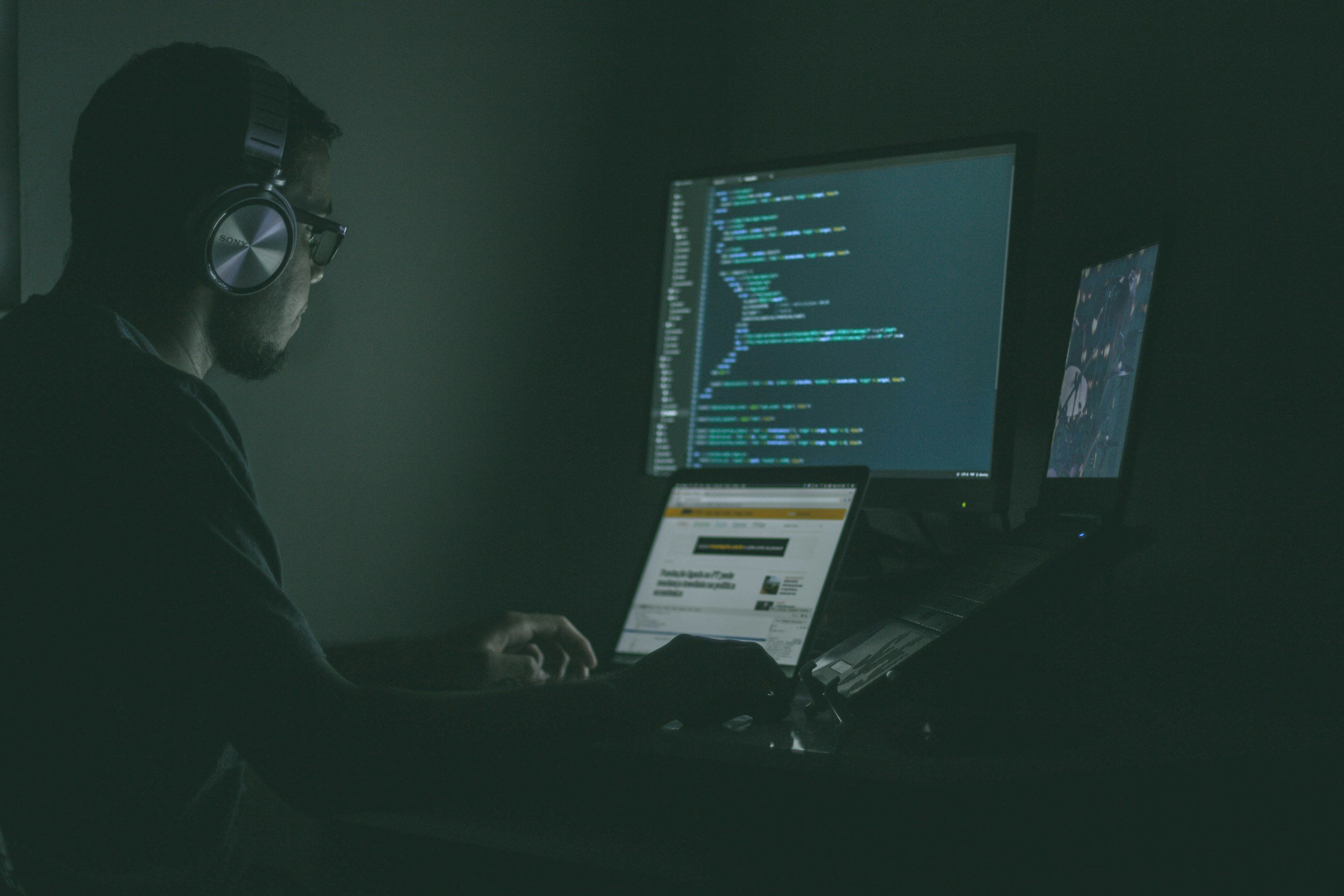 jeune personne assise devant un ordinateur avec des lignes de code sur l'écran, censé symboliser le piratage, la fraude, le vol d'identité, les accusations de fraude, l'arnaqueur