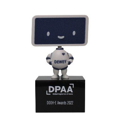 A robot figurine with a computer screen head displaying a cute face, wearing a shirt labeled DEWEY, standing on a black podium that says DPA, awarded at the DOOH-E Awards 2022.