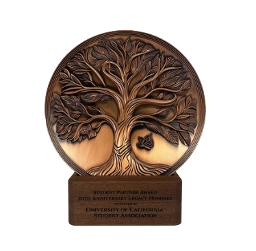 A bronze-colored circular award with a tree and butterfly design, inscribed with 'Student Partner Award, 20th Anniversary Legacy Honor, University of California Student Association'.