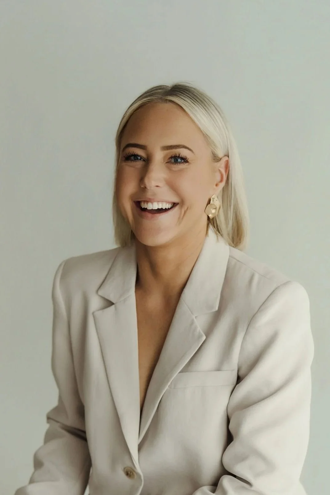 Jess Doyle laughing in a cream blazer