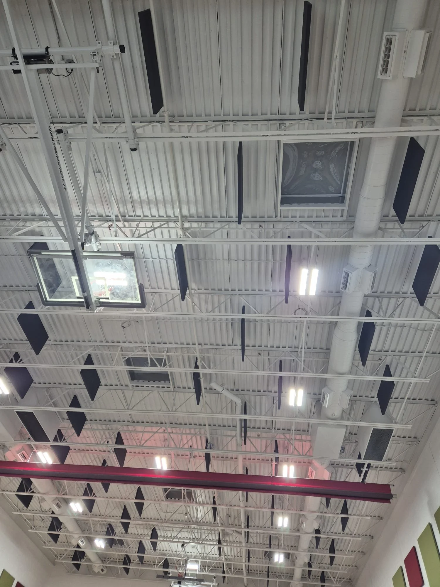 Ceiling of a gymnasium with lights, black sound panels, and ventilation ducts.