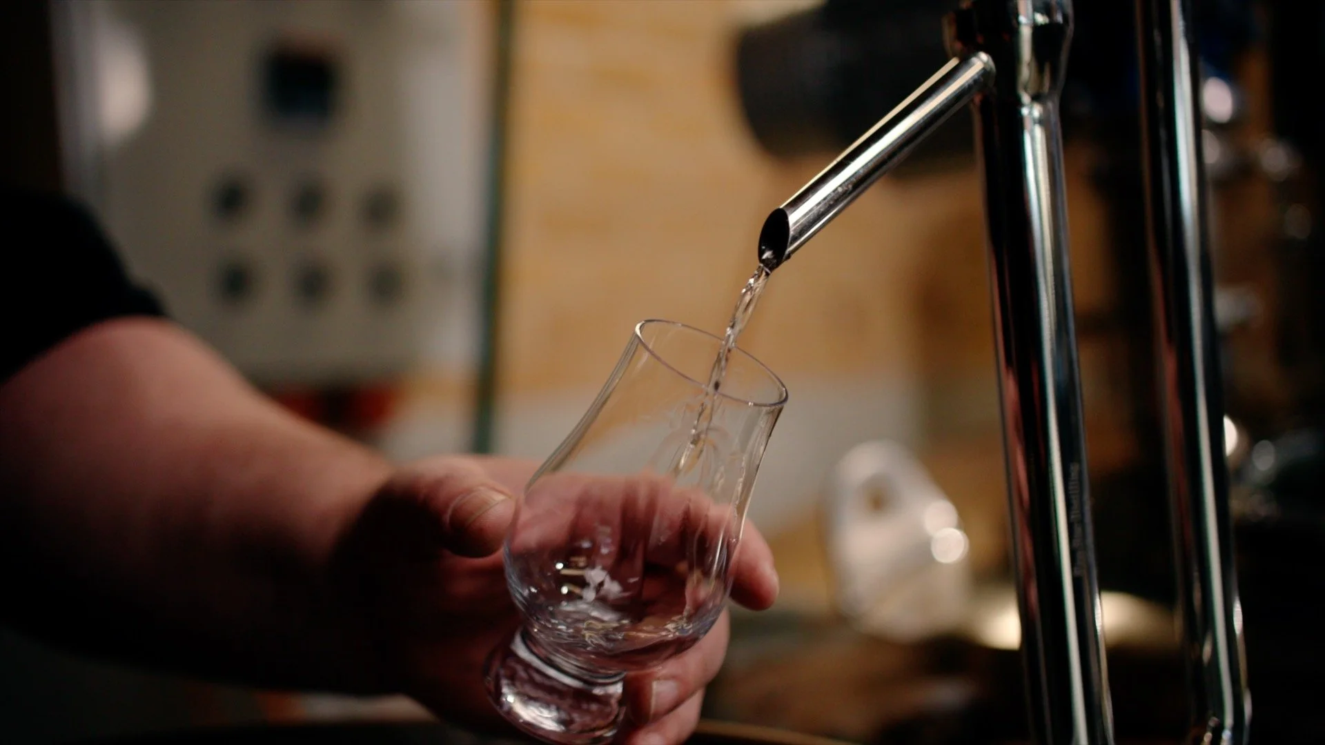 Person catching gin as it is being distilled.