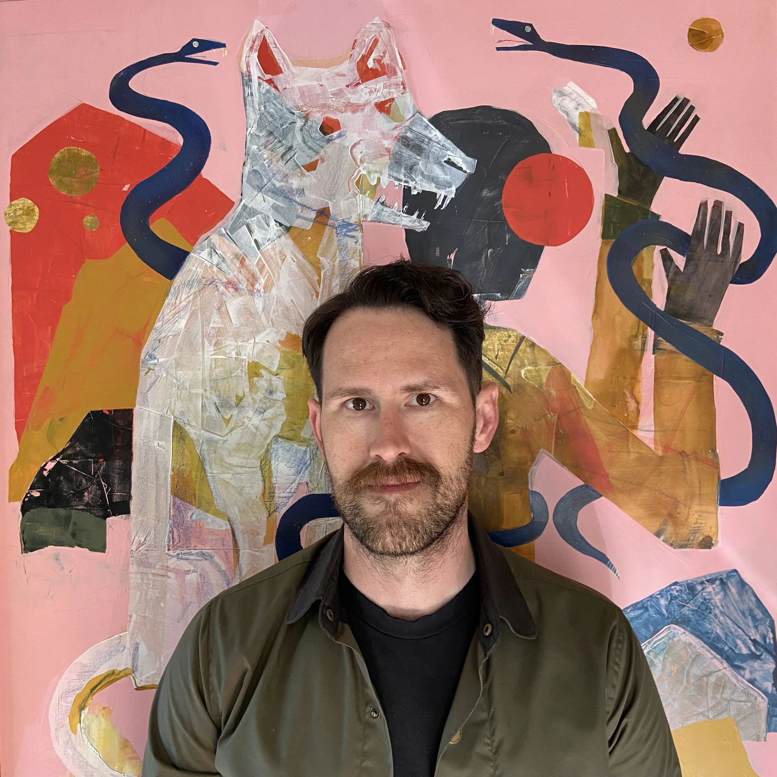 A person with dark hair and a beard is taking a selfie in front of a colorful painting of a white dog with a pink background. The painting includes abstract elements such as serpents, gold circles, and geometric shapes.