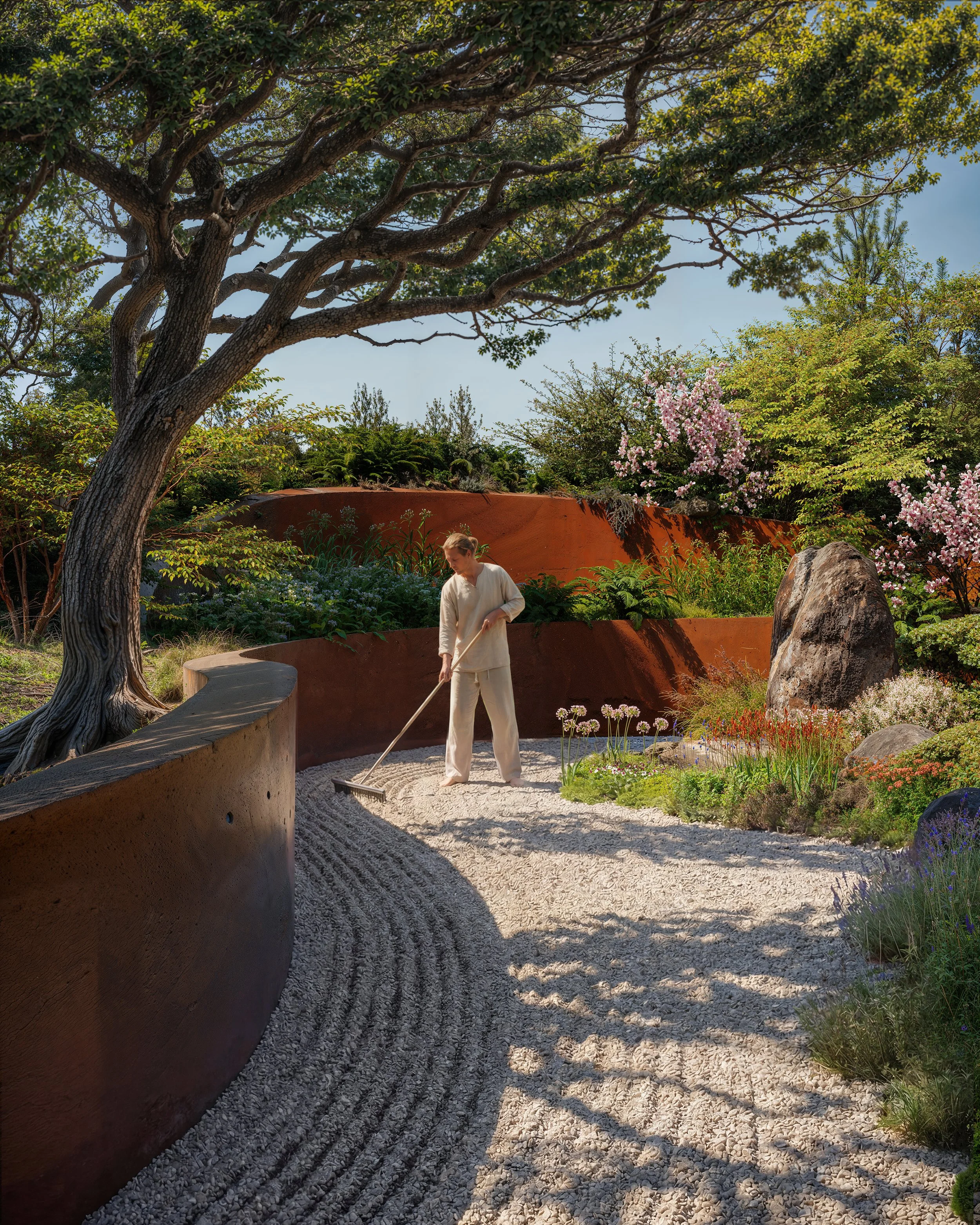 Photorealistic architectural rendering of a contemplative zen garden at the First Responders Resiliency Center in Cotati featuring curved weathered steel walls, gravel meditation paths, mature trees, natural planting, and a tranquil wellness-focused 