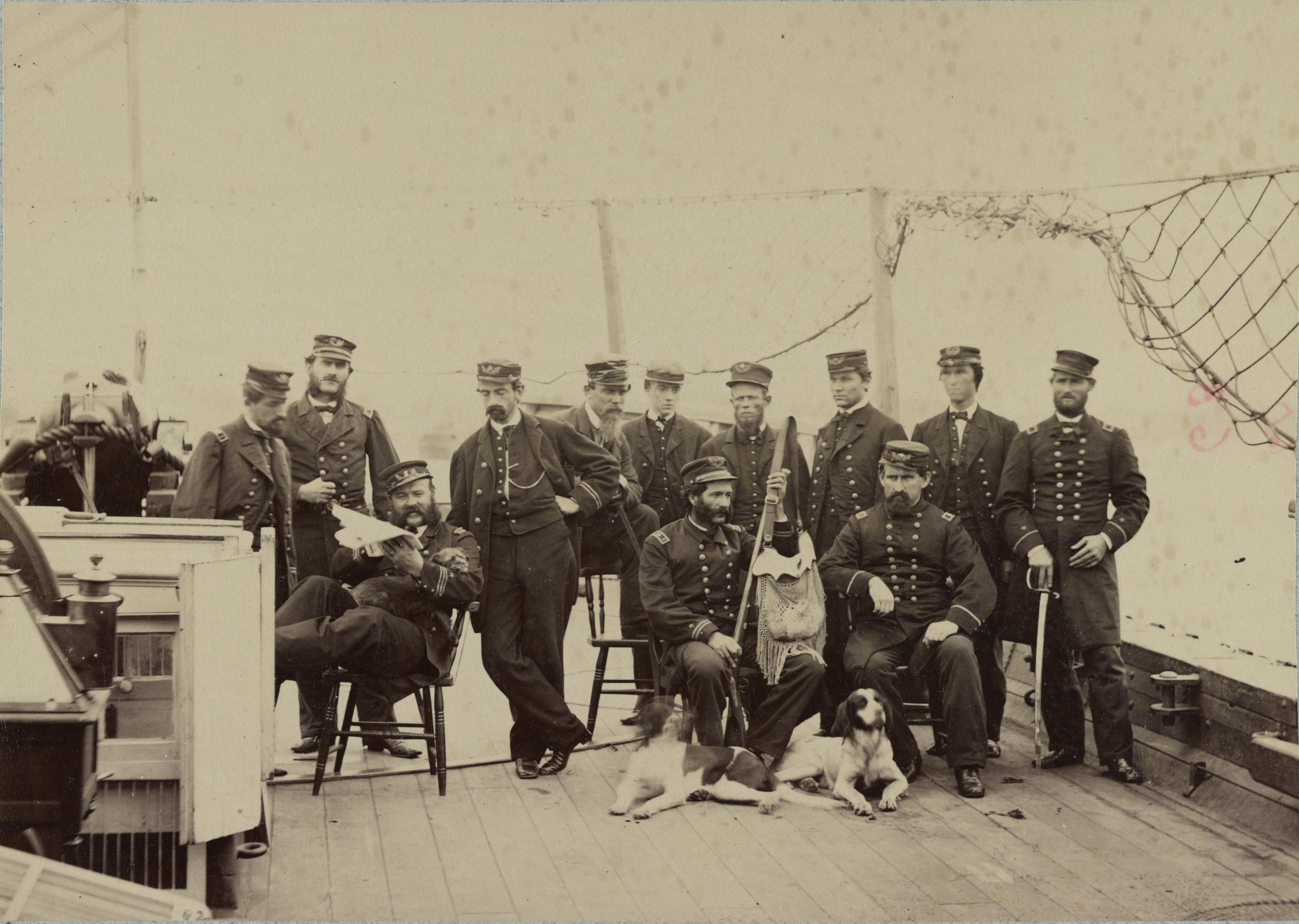Officers pose aboard USS Miami.  Note the two dogs at center, and the small dog in the arms of the seated Lieutenant.