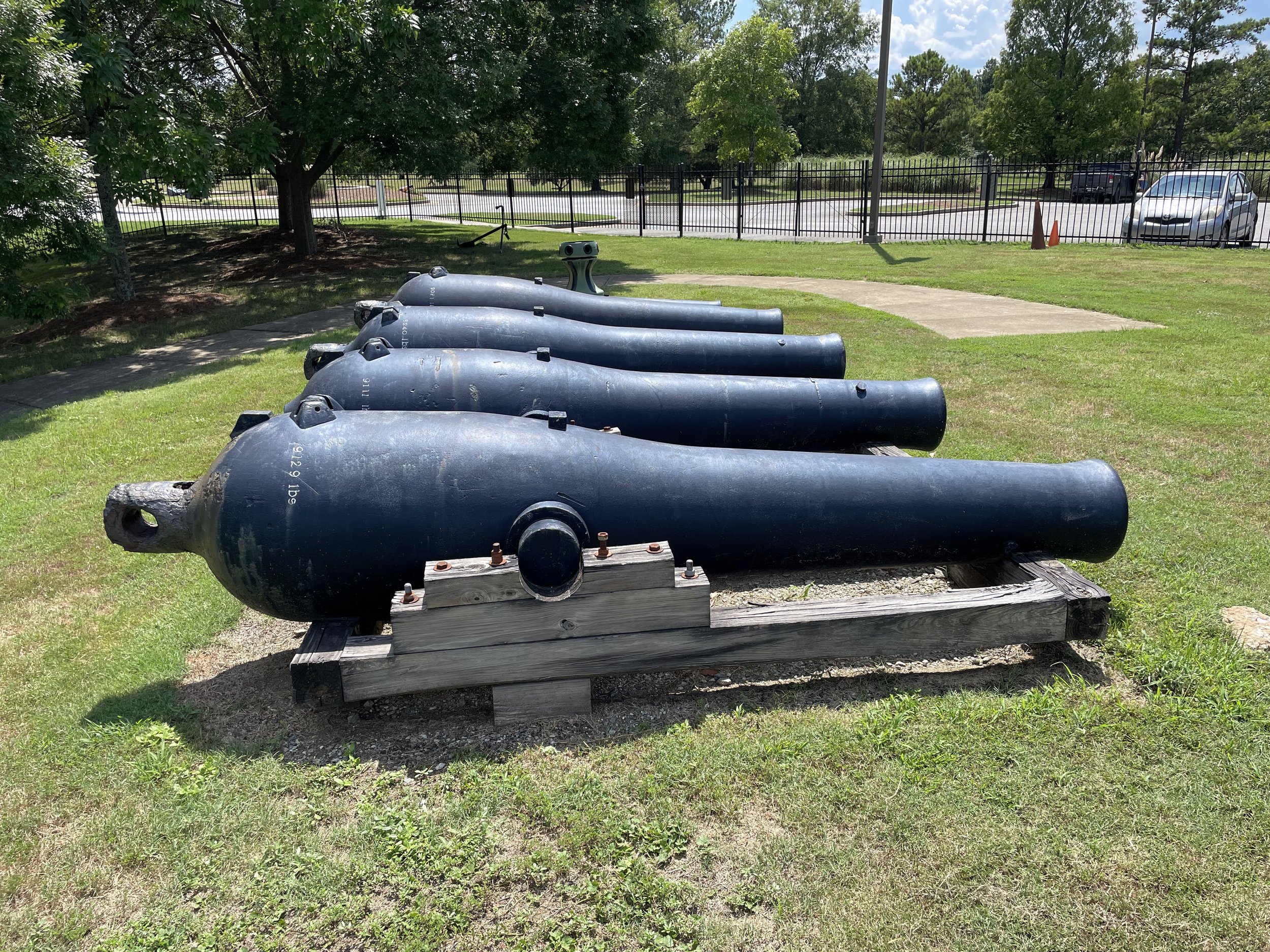 A closely spaced line of Civil War Naval Dahlgren cannons can be seen in a grassy field in this photo