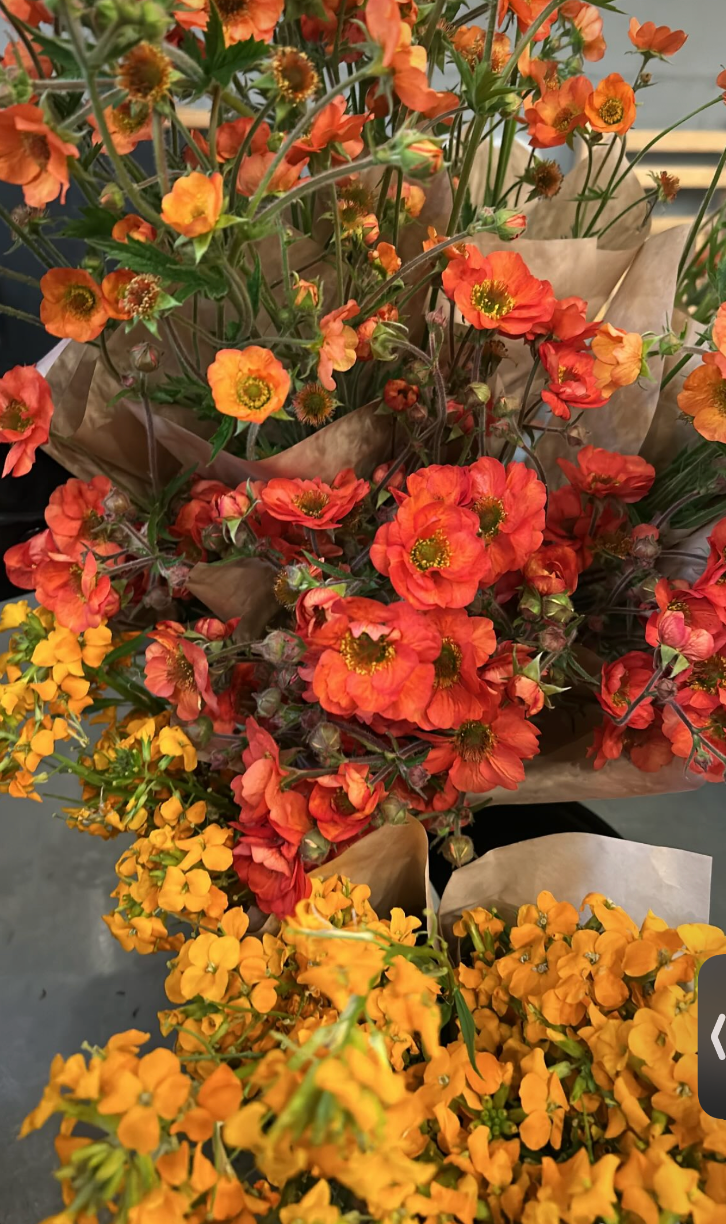 Bouquets of orange and yellow flowers wrapped in brown paper