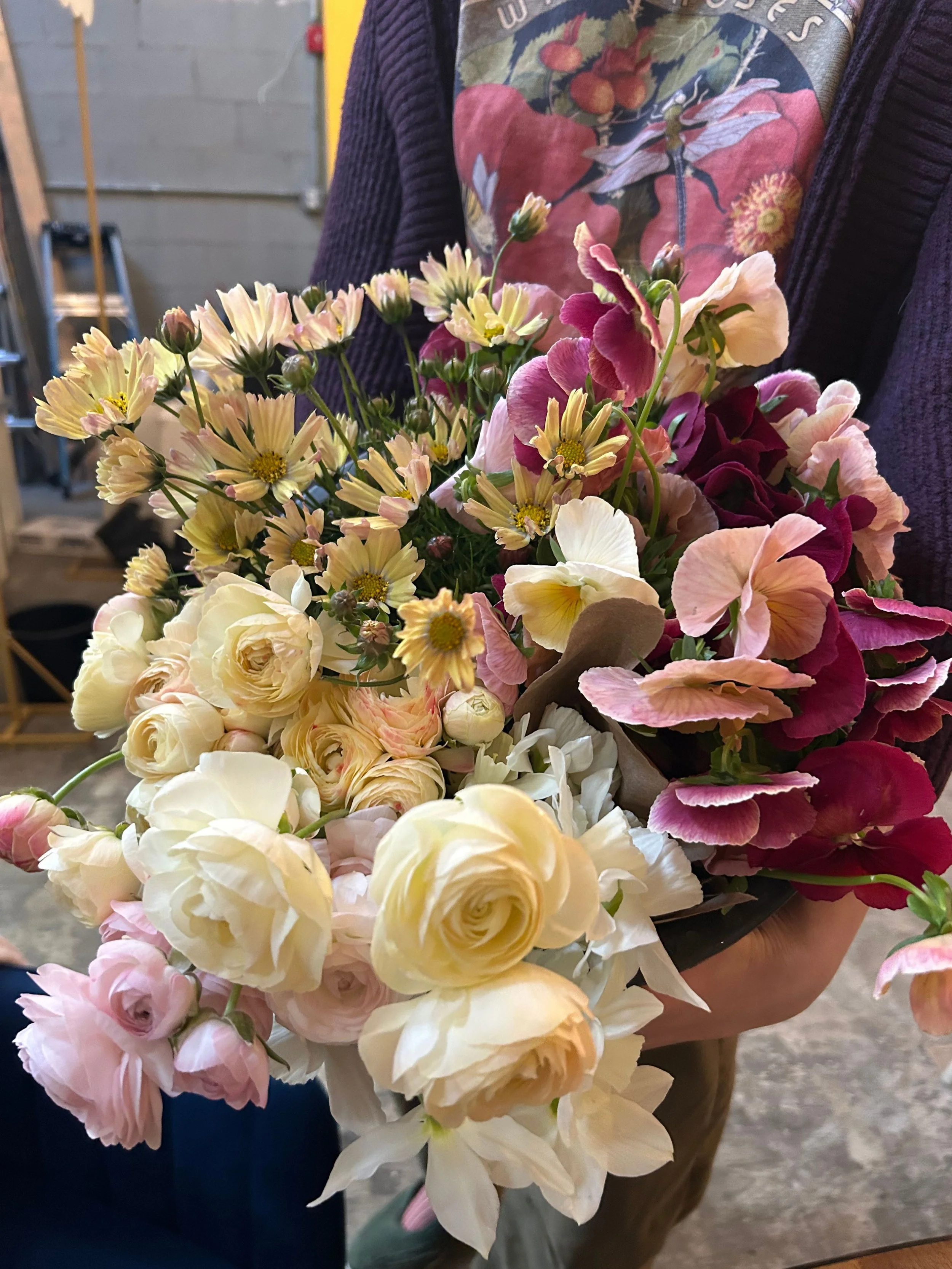 mixed bucket of ranunculus pansies and cosmos