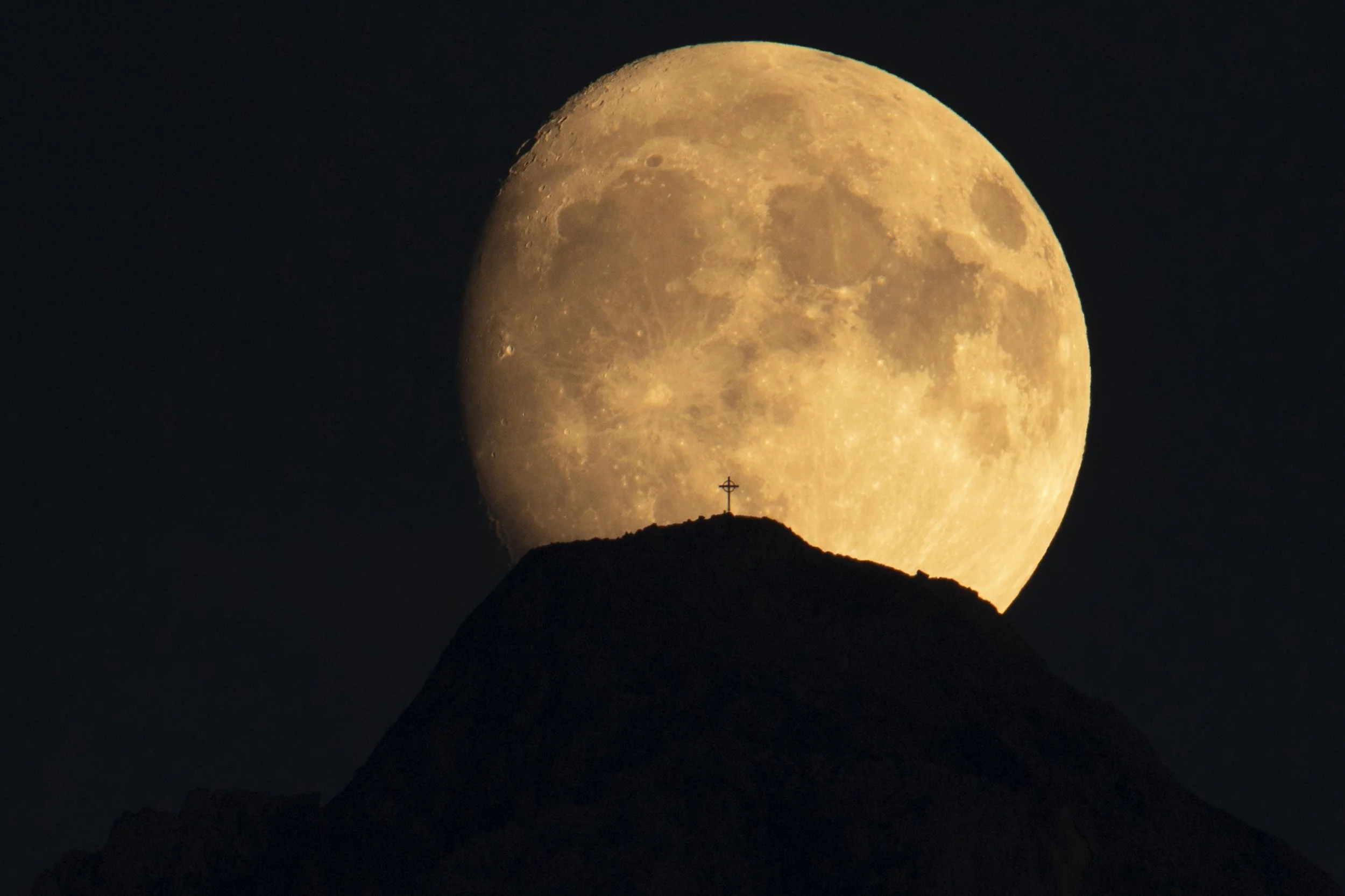 Der Zimba Berg als markante Silhouette mit einem Mond und Gipfelkreuz sichtbar