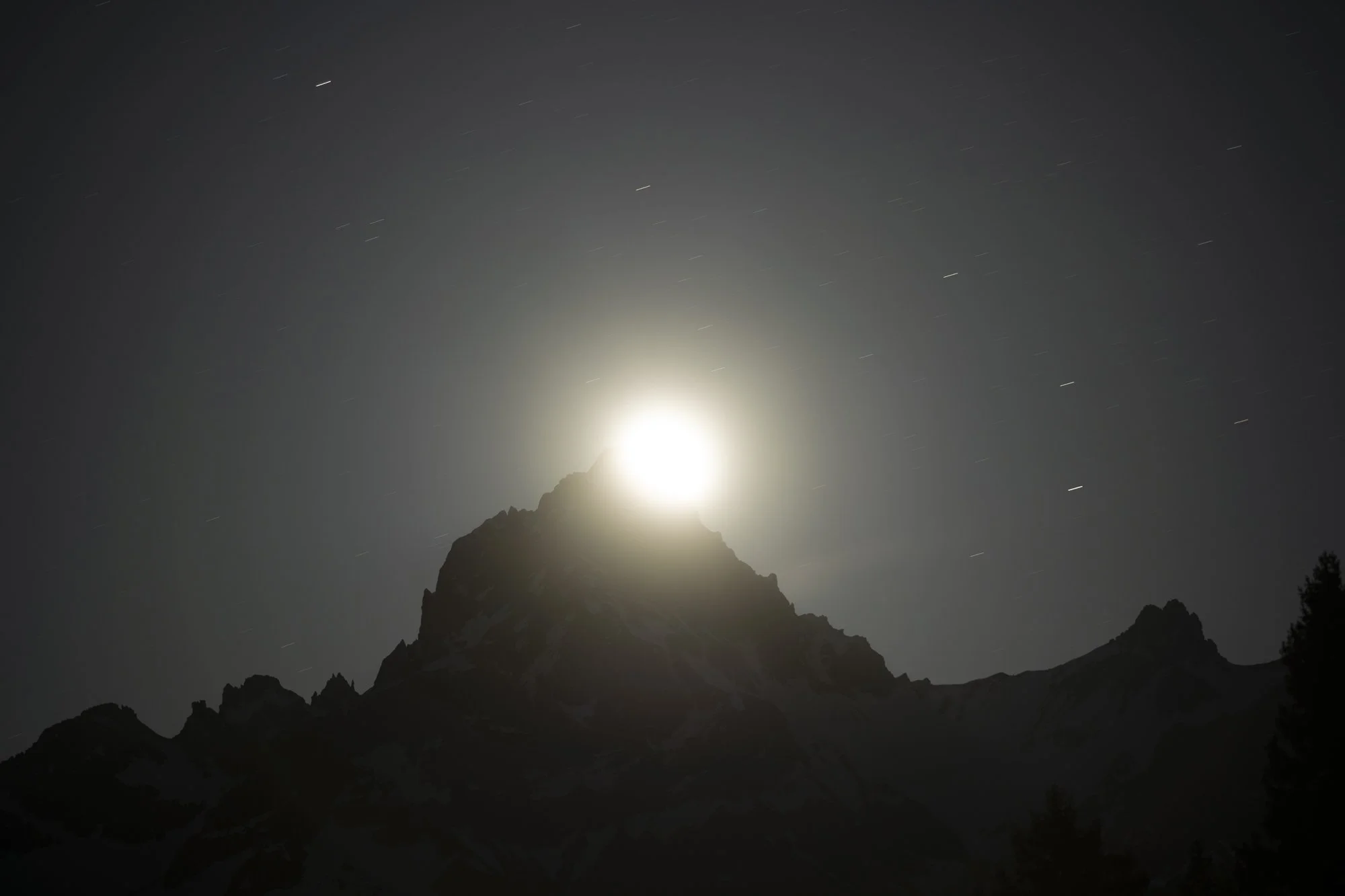 Der Zimba Berg als Silhouette mit einem High Key Mond und sichtbarem Gipfelkreuz