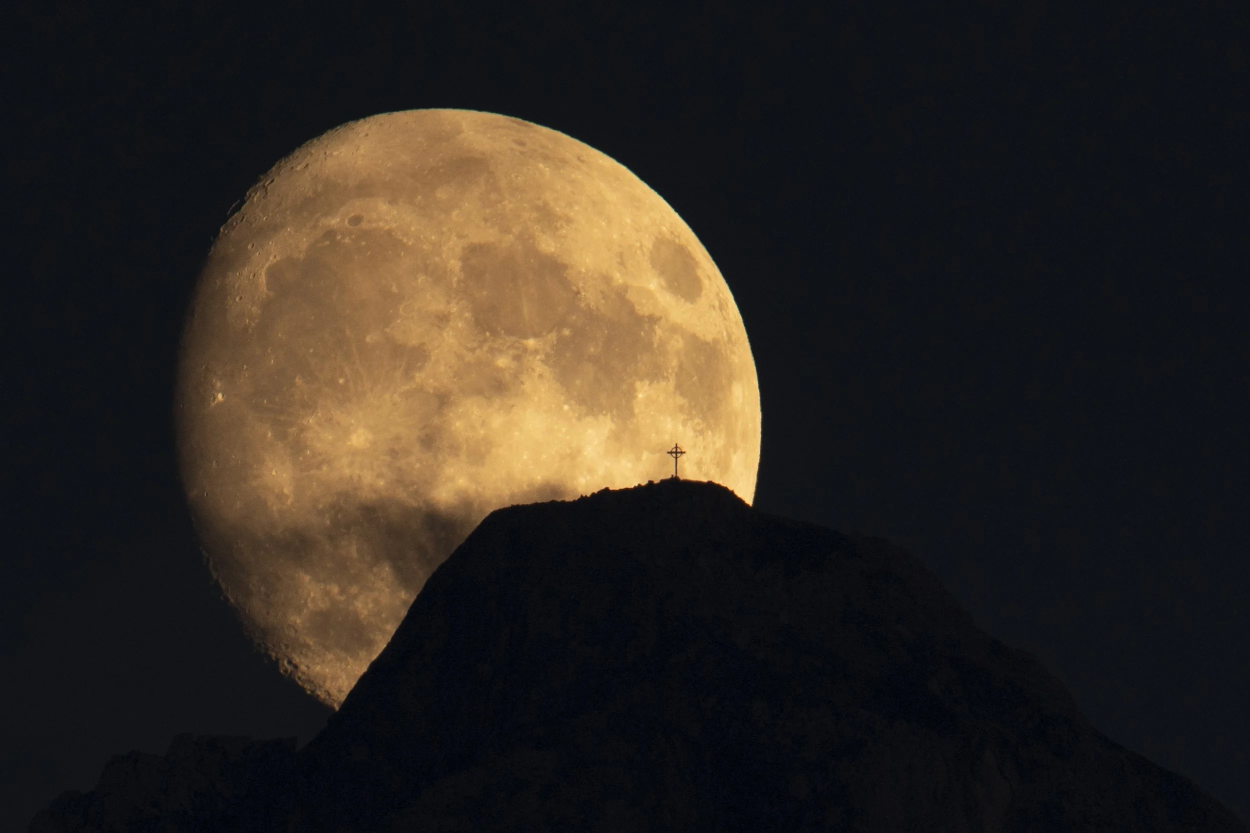 Der Zimba Berg als markante Silhouette mit einem Mond und Gipfelkreuz sichtbar