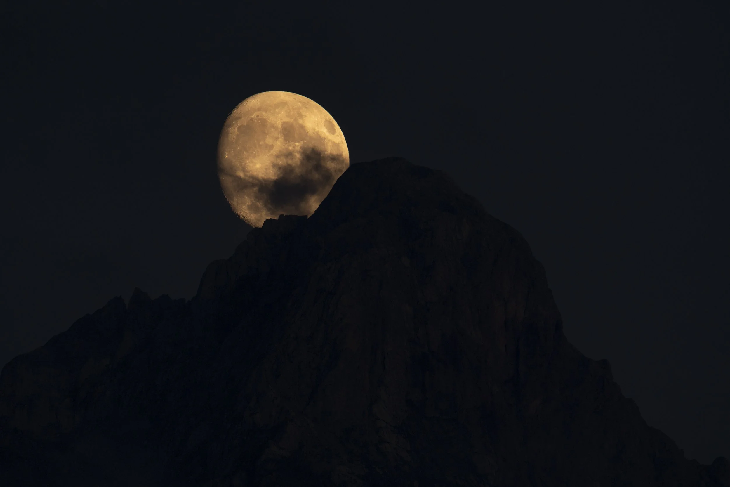 Der Zimba Berg als markante Silhouette mit einem Mond und Gipfelkreuz sichtbar