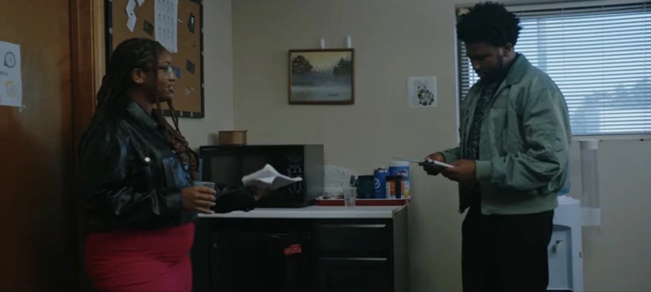 A woman and a man talking in a small office.