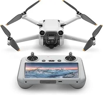 A white drone with four propellers positioned above a gray remote control with a screen displaying a mountain landscape.